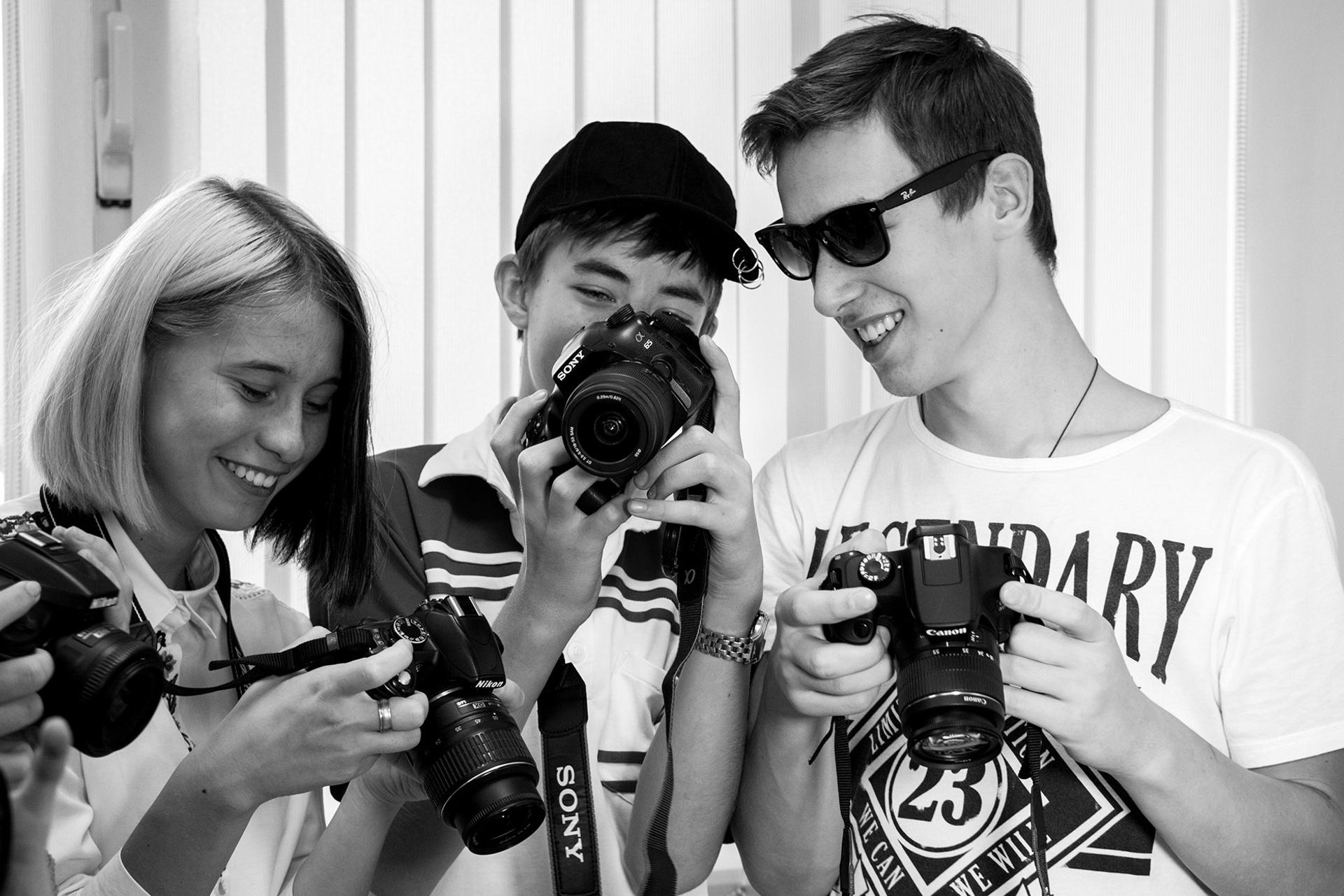 Ученики фотошколы весело и радостно рассматривают друг у друга фотоснимки, получившиеся на практике.