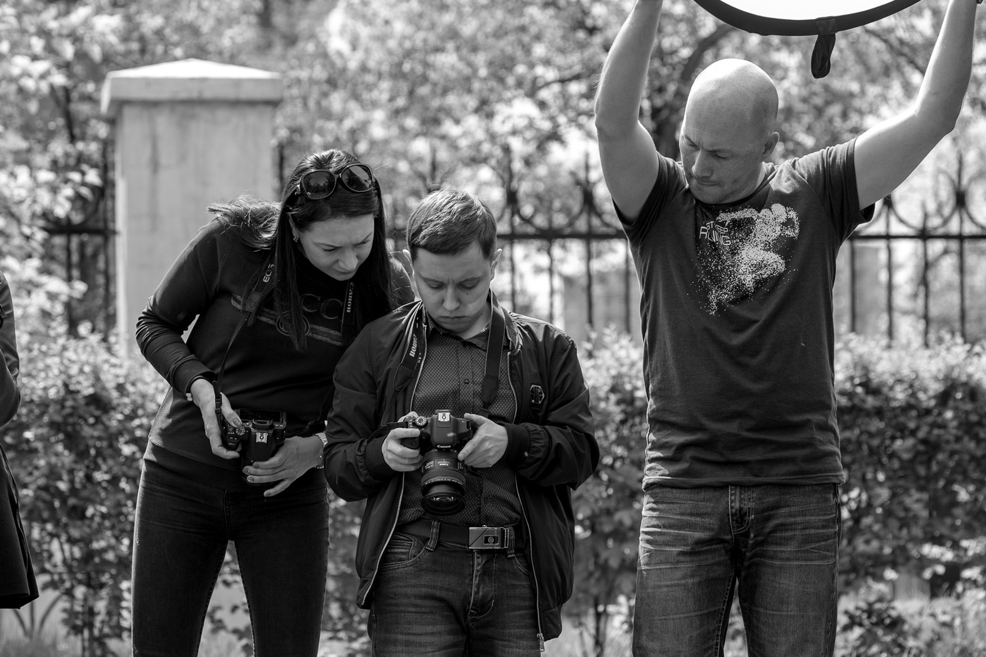 Фотографы проходят практику работы с отражателем в условиях съёмки уличного портрета в парке.
