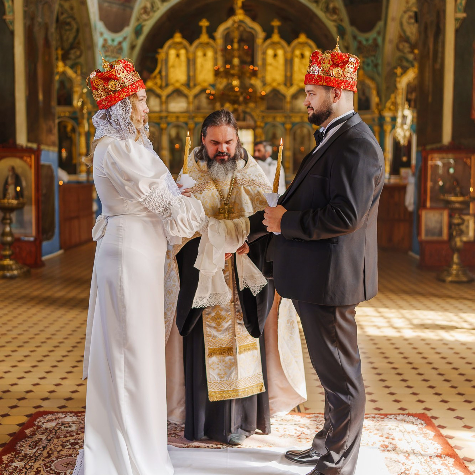 Жених и невеста в венцах во время православного венчания в храме