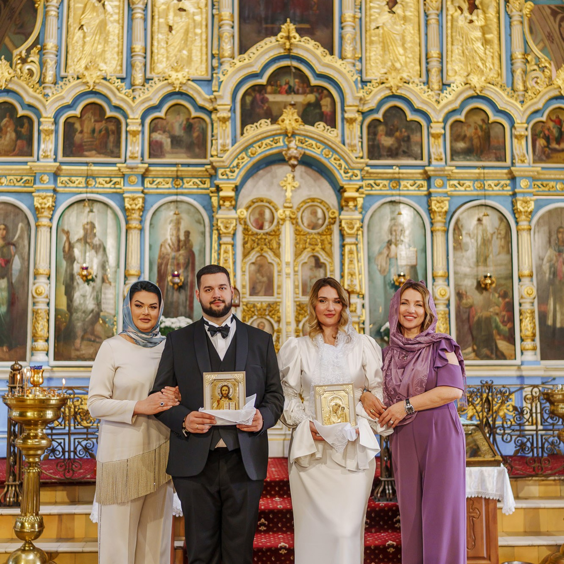 Молодожёны с иконами у иконостаса после православного венчания