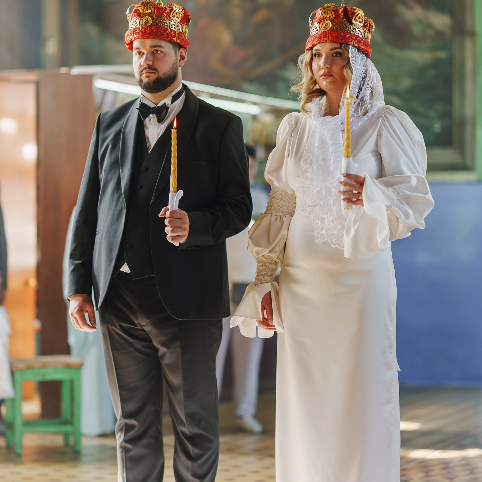 Жених и невеста в венцах со свечами во время православного венчания