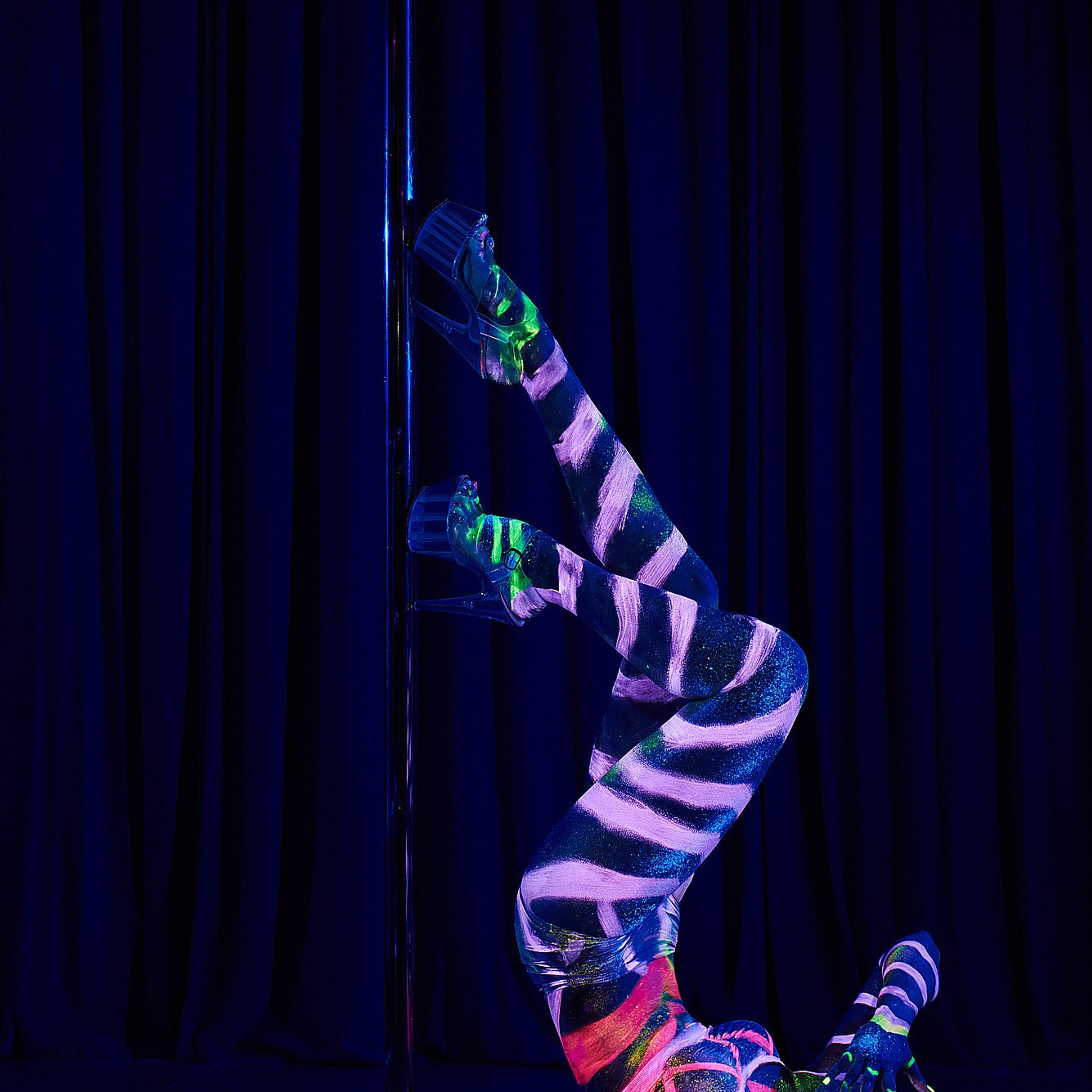Вытянутая вертикальная поза танцовщика, растворяющегося в флуоресцентном свете, создаёт ощущение вибрации и движения. Профессиональная постановочная съёмка, Москва и Истринский район.