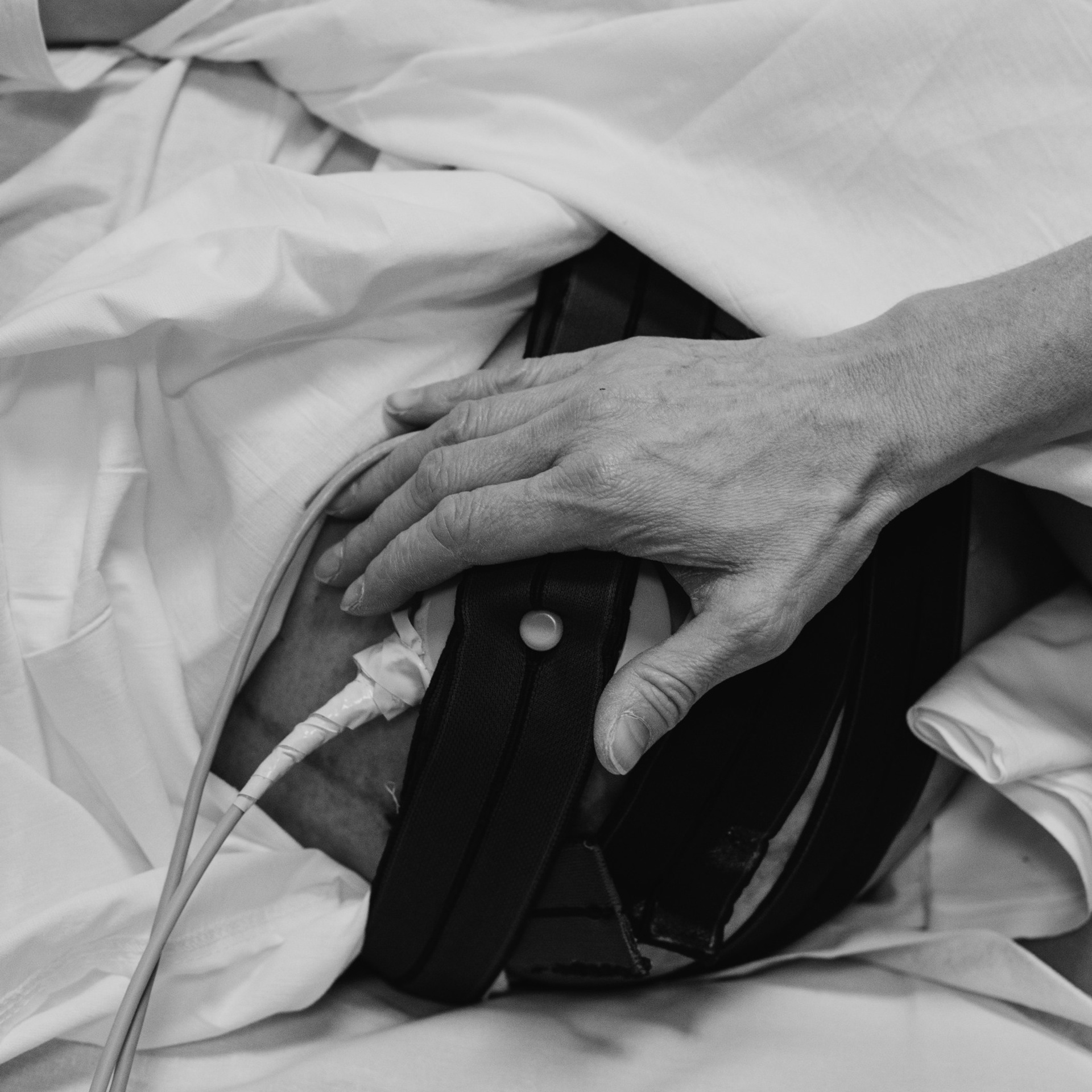 Фото родов. Будущая мама лежит на КТГ. Рука акушерки лежит на животе мамы. Крупный план