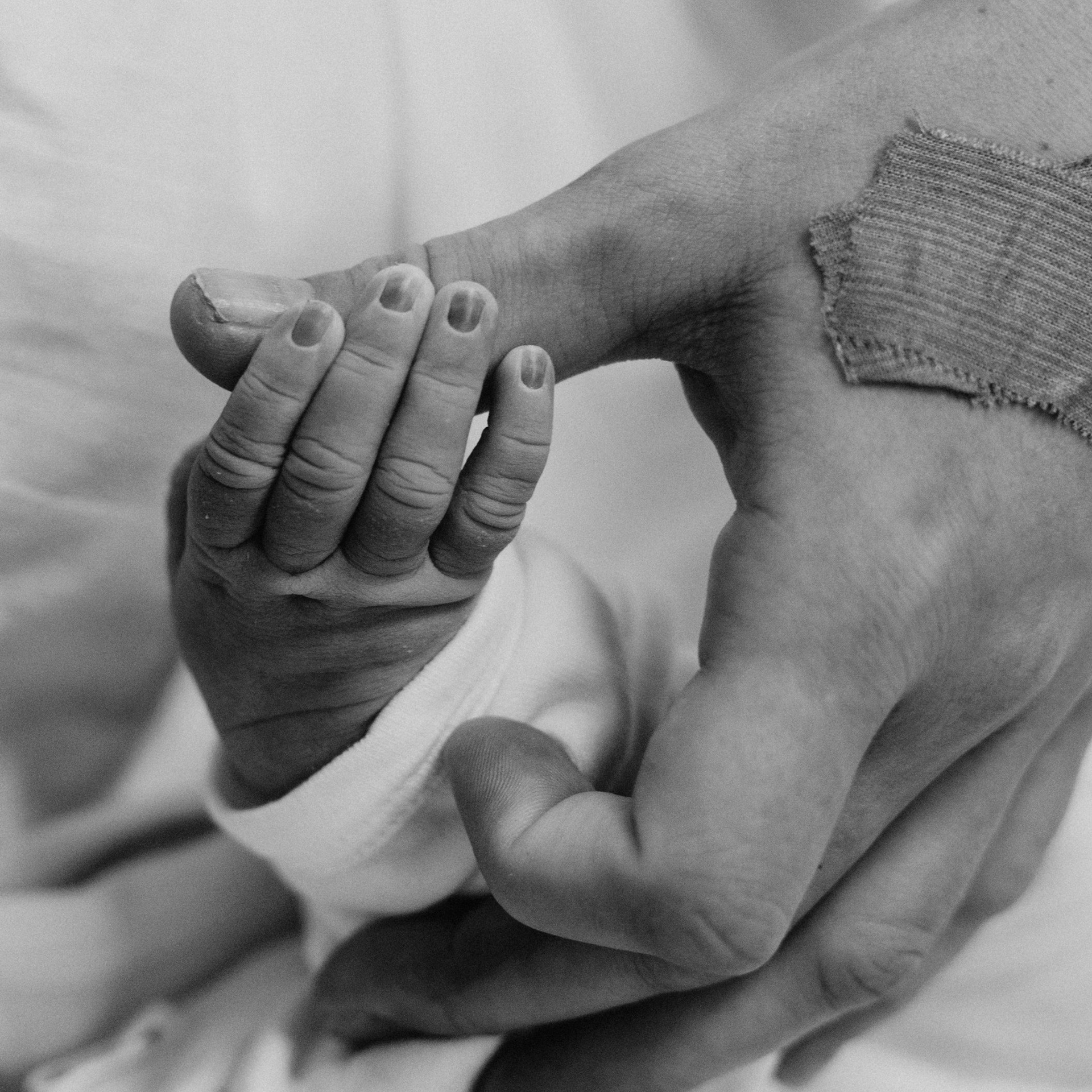 Крупный план. фото родов. Мама держит за руку только что родившегося ребенка.