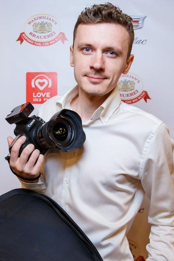 фотограф в белой рубашке на белом фоне с фотоаппаратом