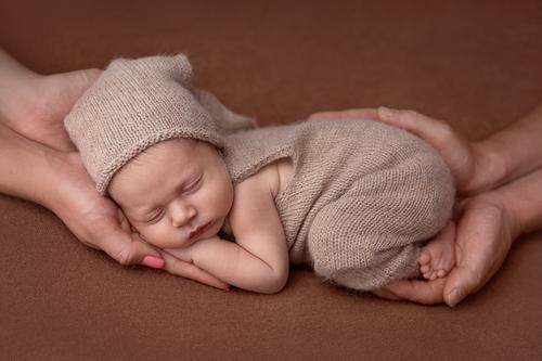 новорожденного малыша обнимают руки папы и мамы