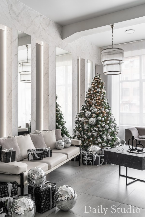 новогодний интерьер в студии для фотосессии: белый диван, елка, мраморная стена