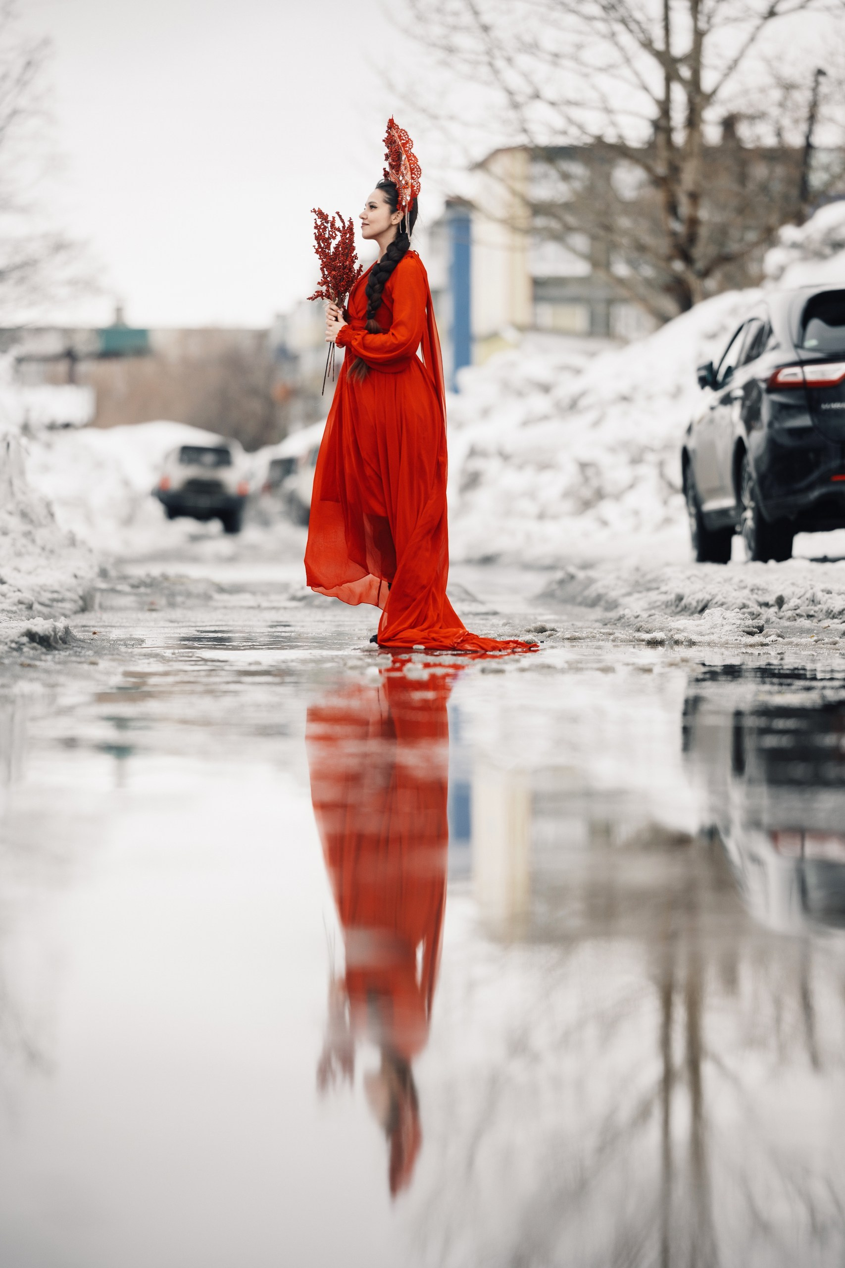 Художественная фотосессия девушки в красном платье среди тающего снега, контраст весны и городского пейзажа, портретная съёмка на улице