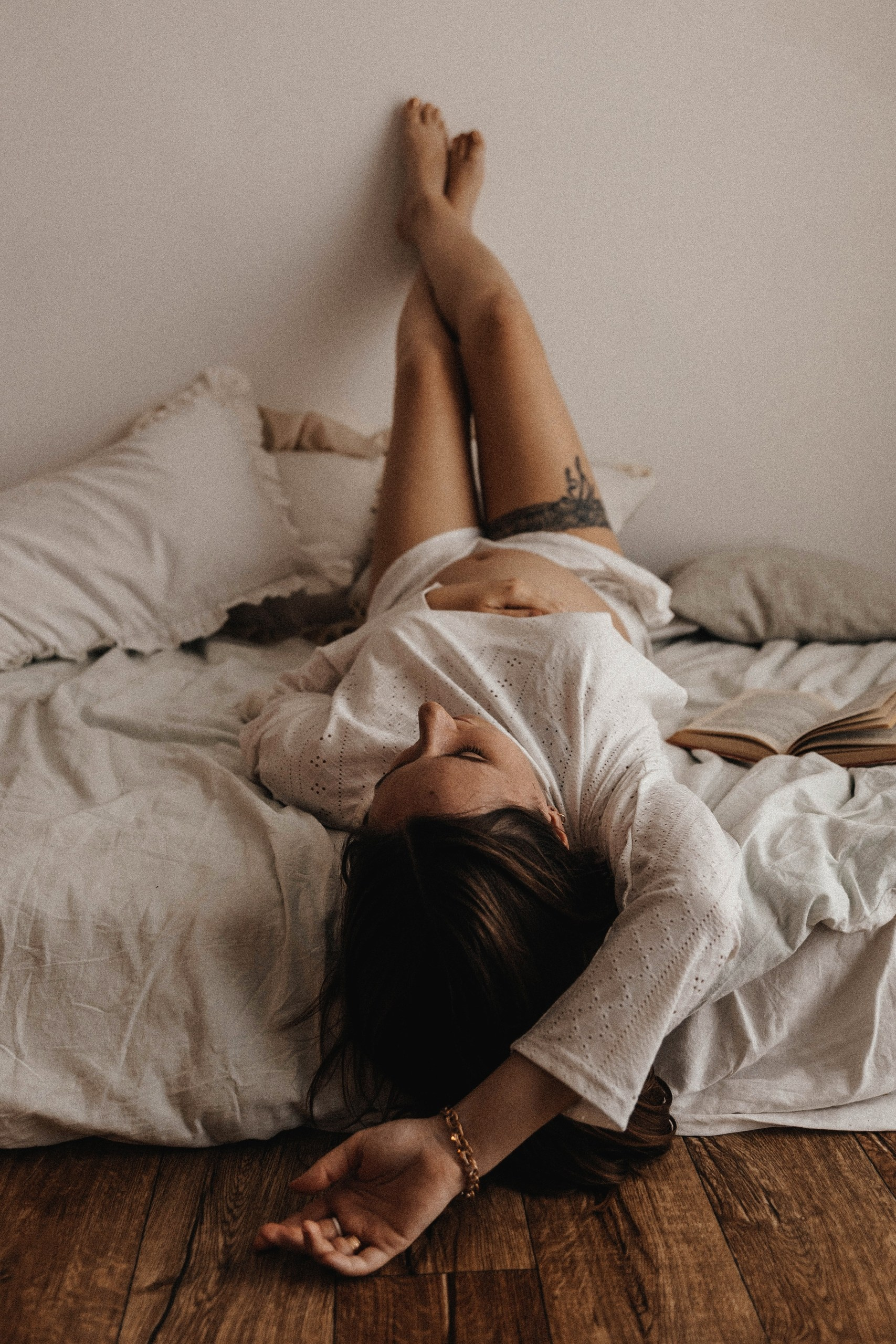 Фотография беременной со скрещенными ногами в пастельных тонах