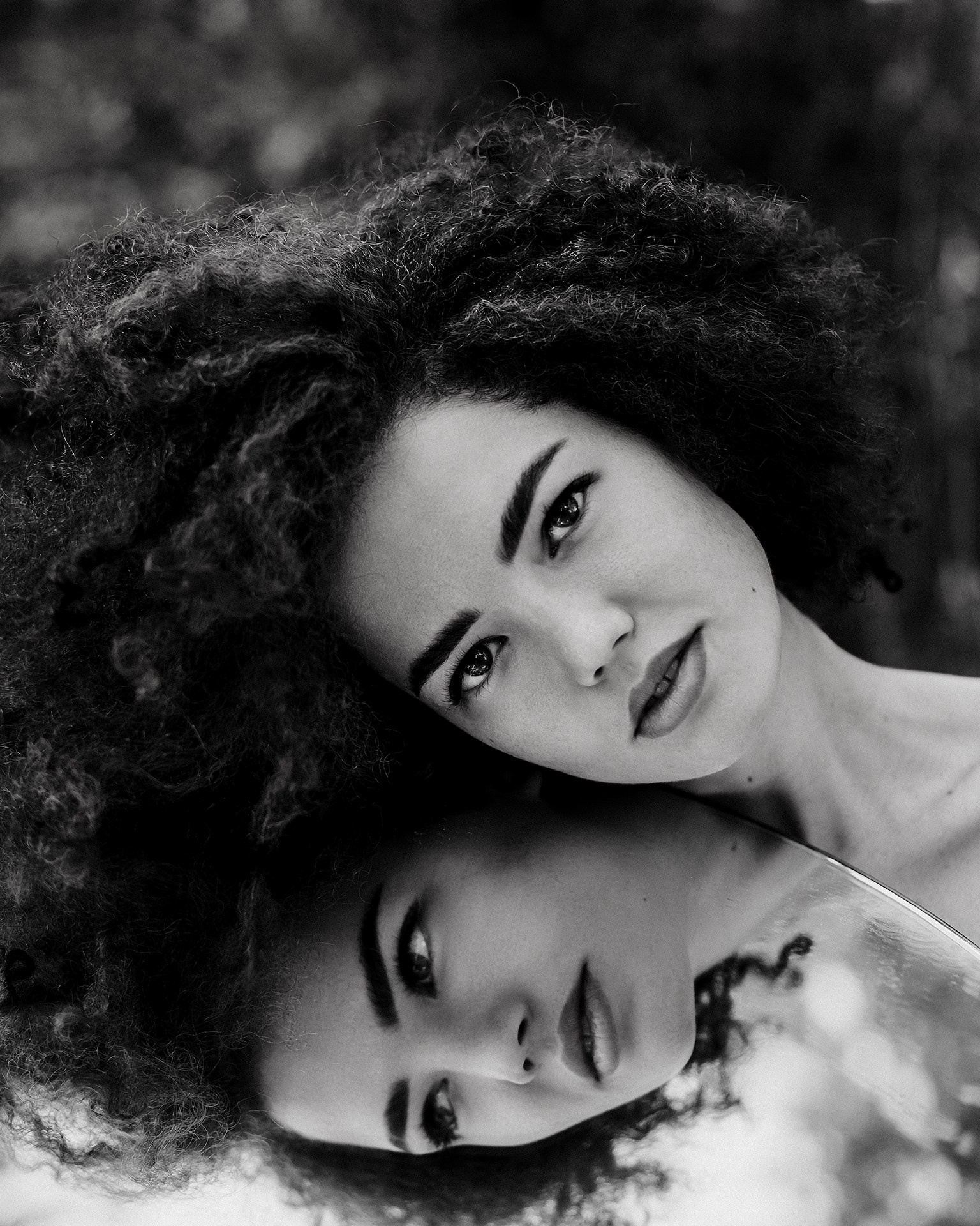 Съемка с зеркалом на отражение, молодая девушка с пышными волосами позирует с зеркалом