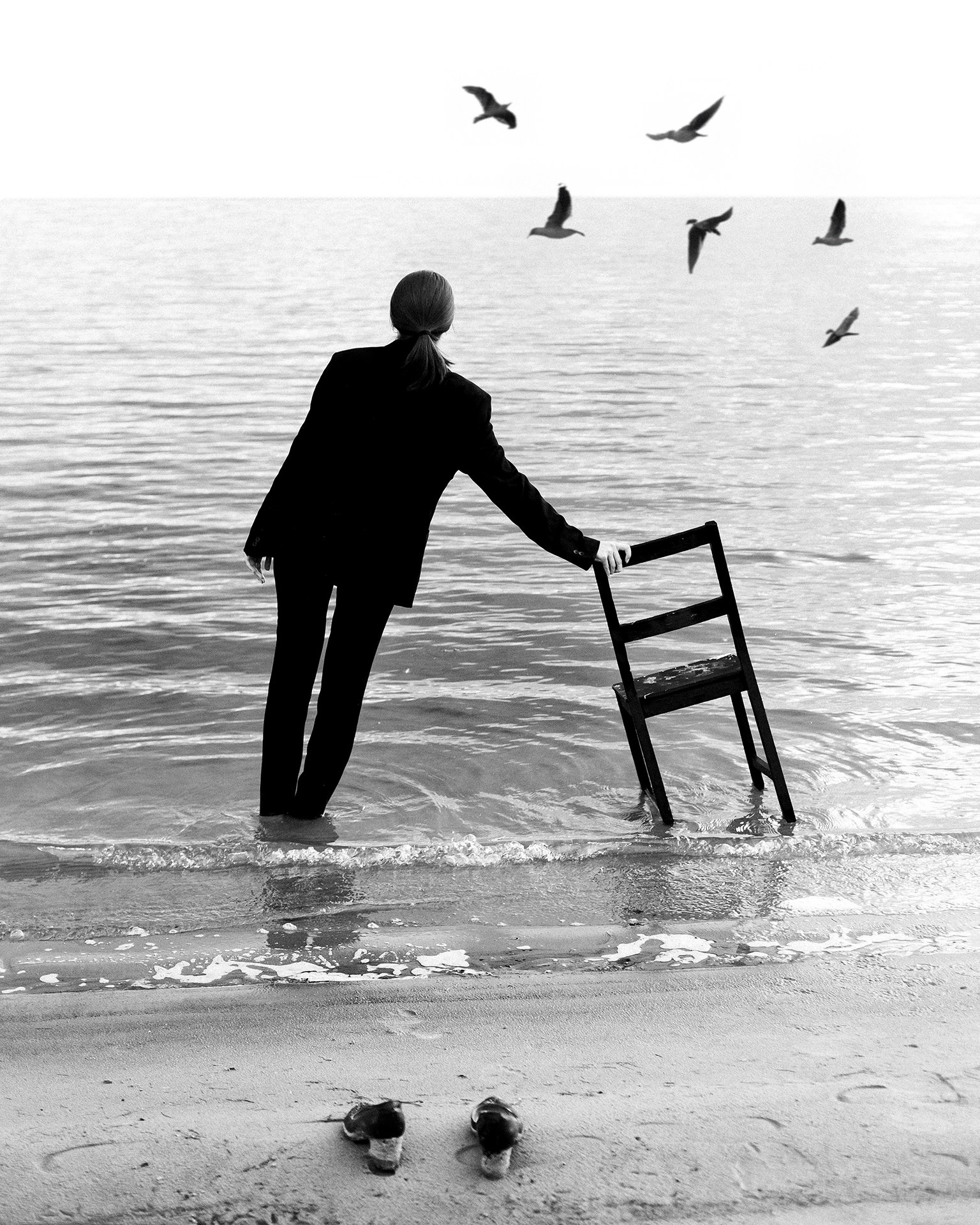 Девушка в черном пиджаке стоит в воде и опирается рукой на стул, творчество в воде на улице Казань