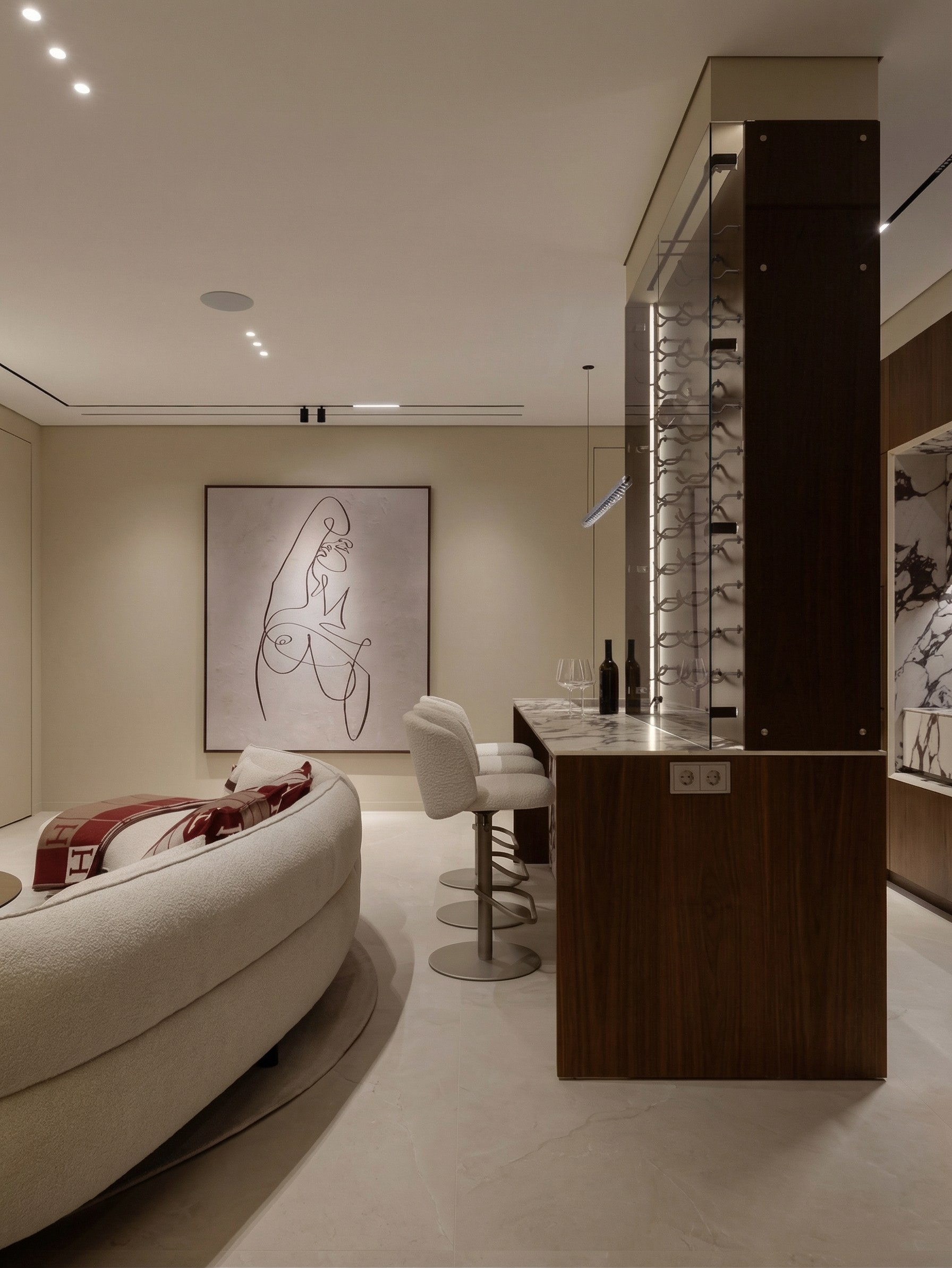 Зонирование кухни-гостиной в квартире 85 м² от Валерии Котович: барный остров из дерева и камня, радиусный диван и архитектурный сценарий освещения.