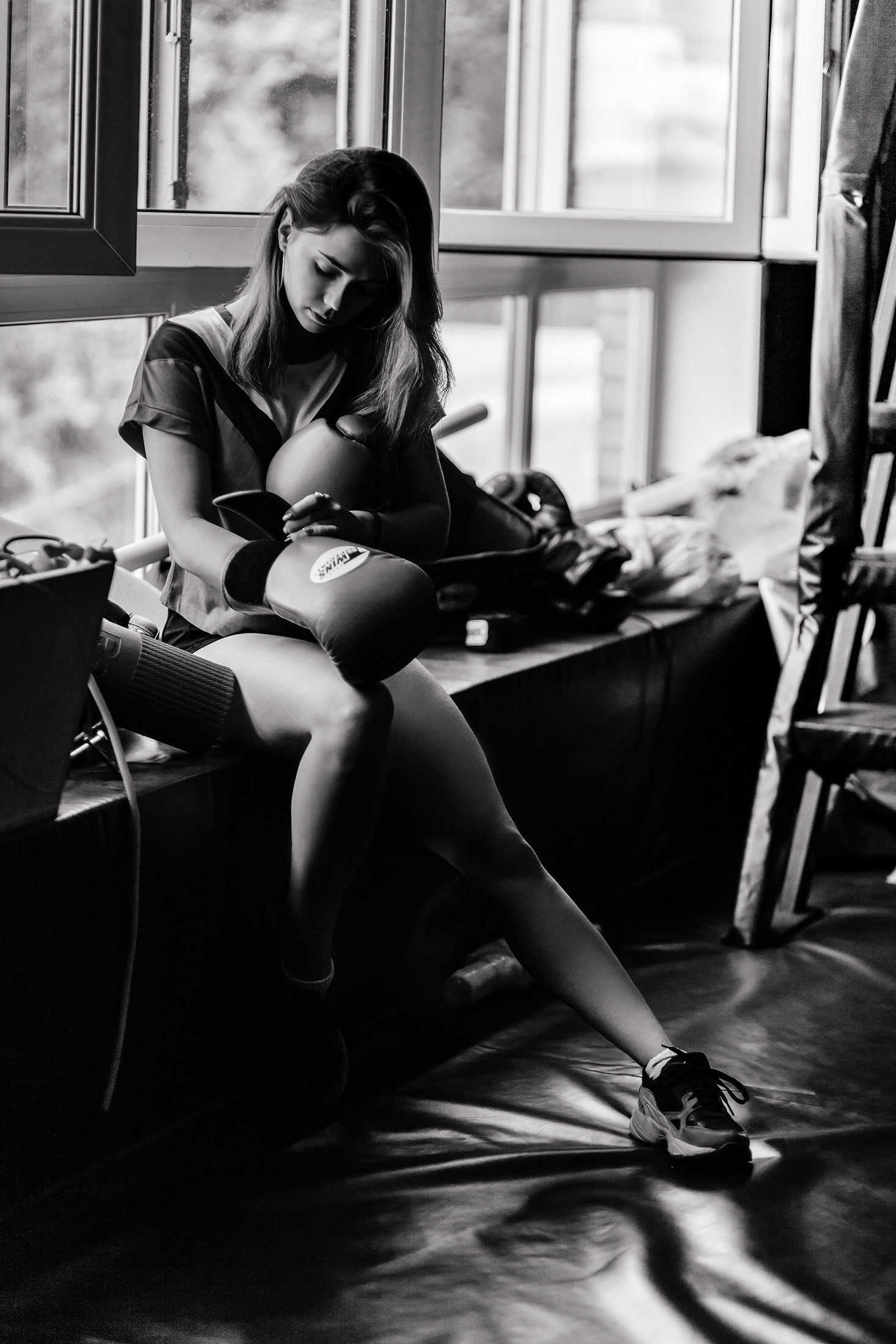 Спортивная фотосессия девушки с боксерскими перчатками в тренажёрном зале. Черно белая спортивная фотография.