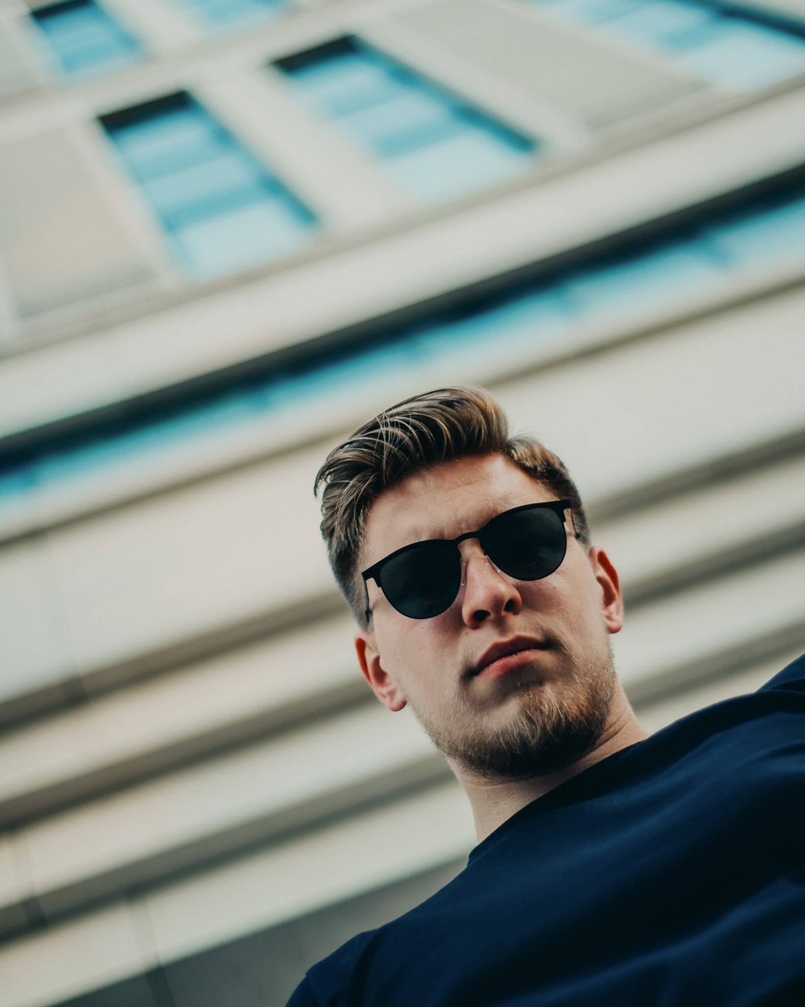 Фотограф Роман Романов — портрет снизу вверх парня с бородой на фоне здания