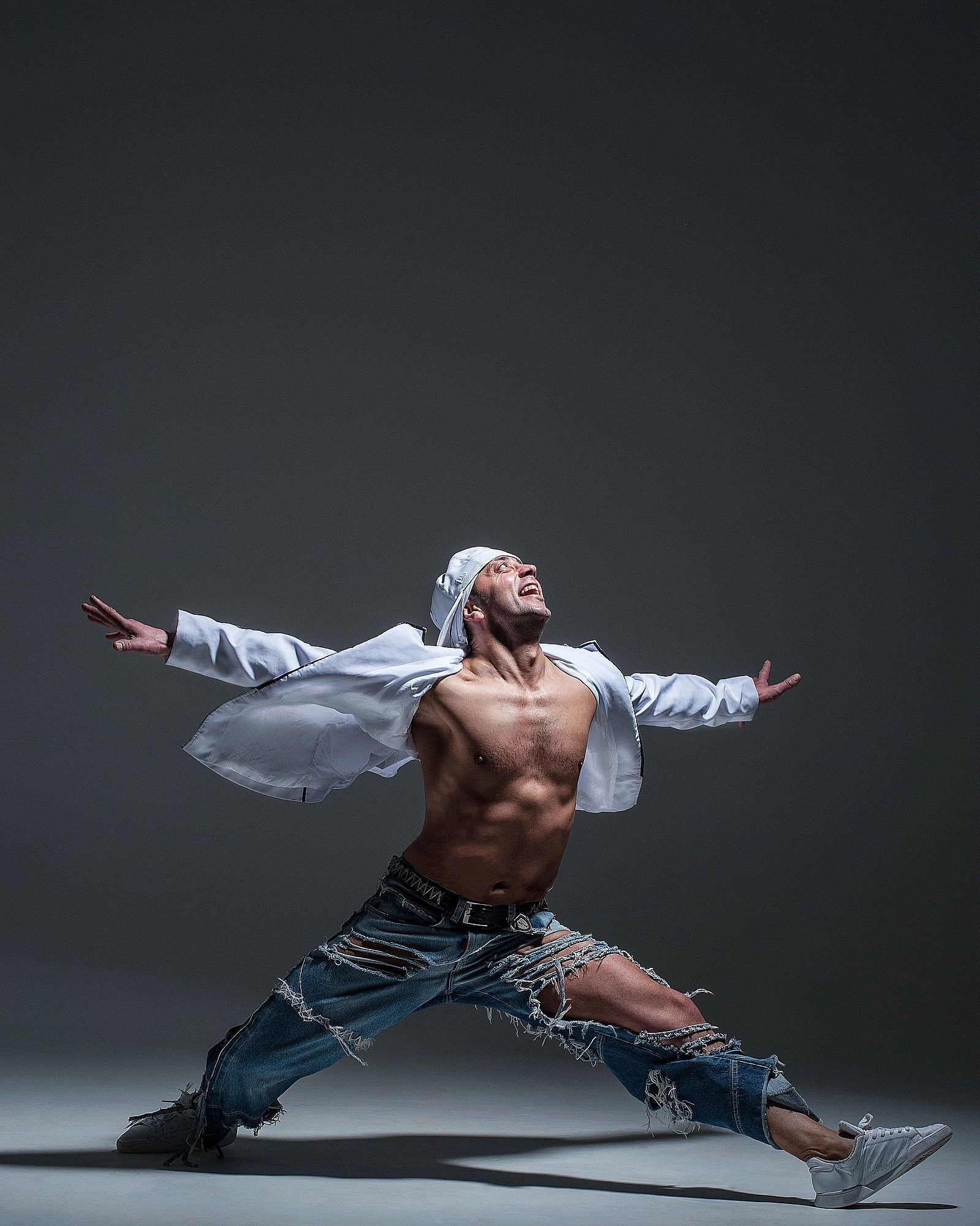 Танцор стоит в широкой позиции с расправленными руками, создавая строгую симметрию позы. Атлетичная танцевальная фотография — Москва, Истринский район.