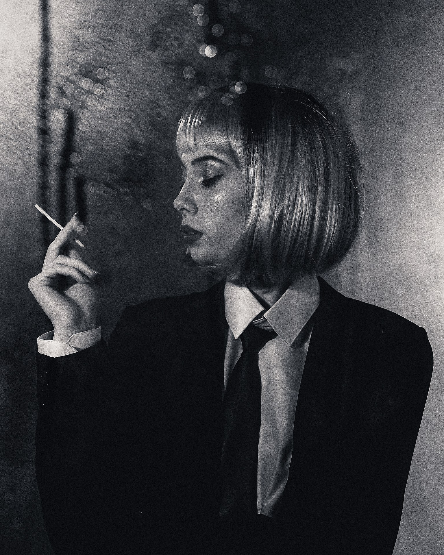 Молодая девушка в парике и пиджаке с сигаретой в руке. Съемка через пластиковую панель в студии