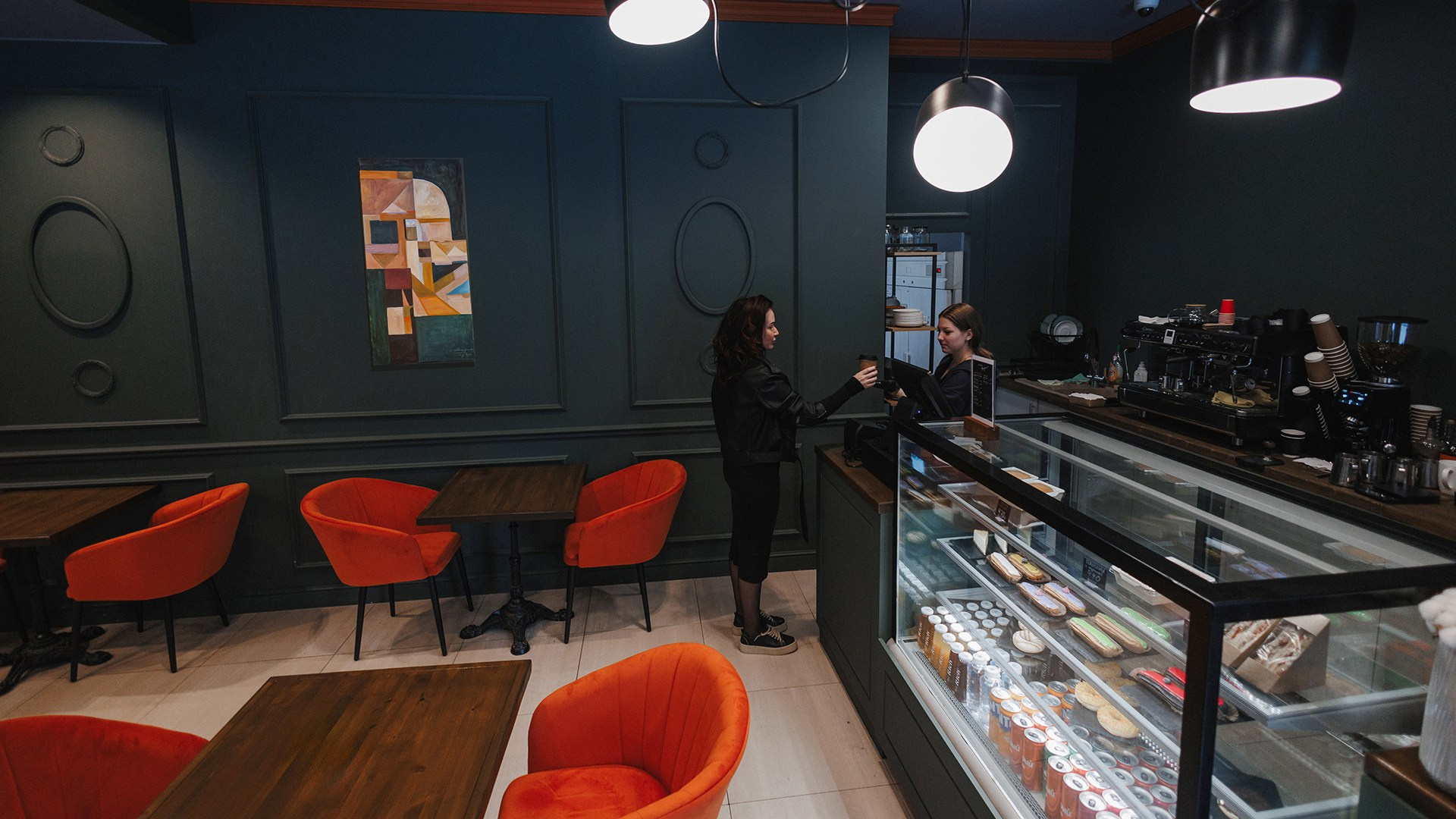 Бариста улыбается и общается с гостем за стойкой.