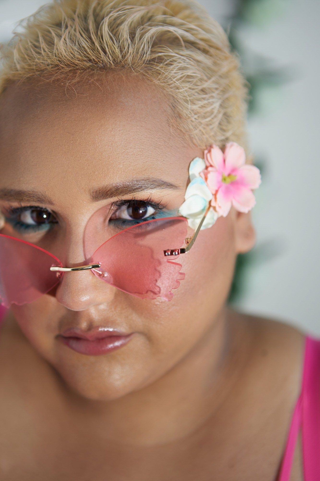 Close-up beauty portrait of Doriane Cannon wearing pink-tinted sunglasses with a floral detail.