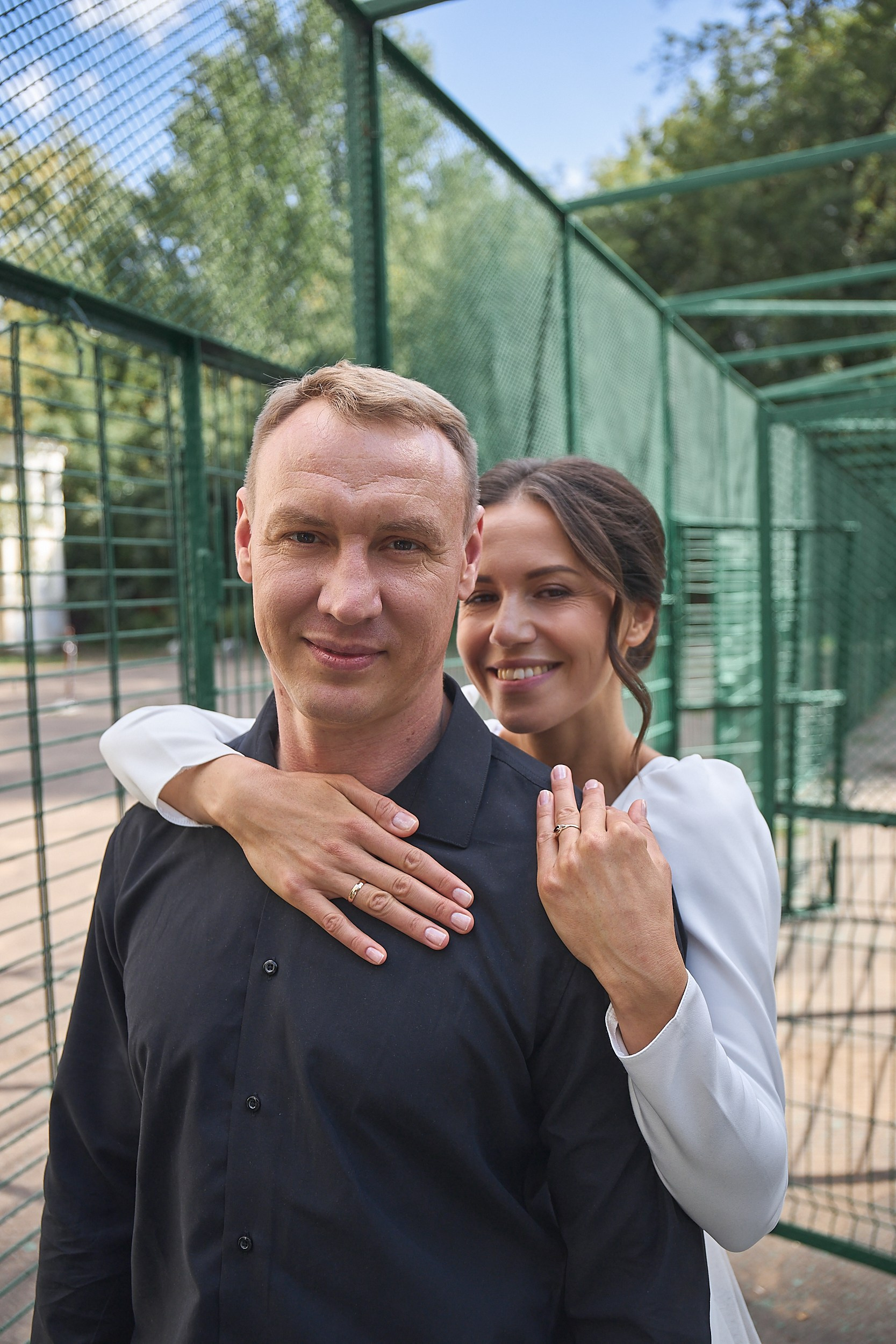 Невеста в белом платье обнимает жениха в черной рубашке