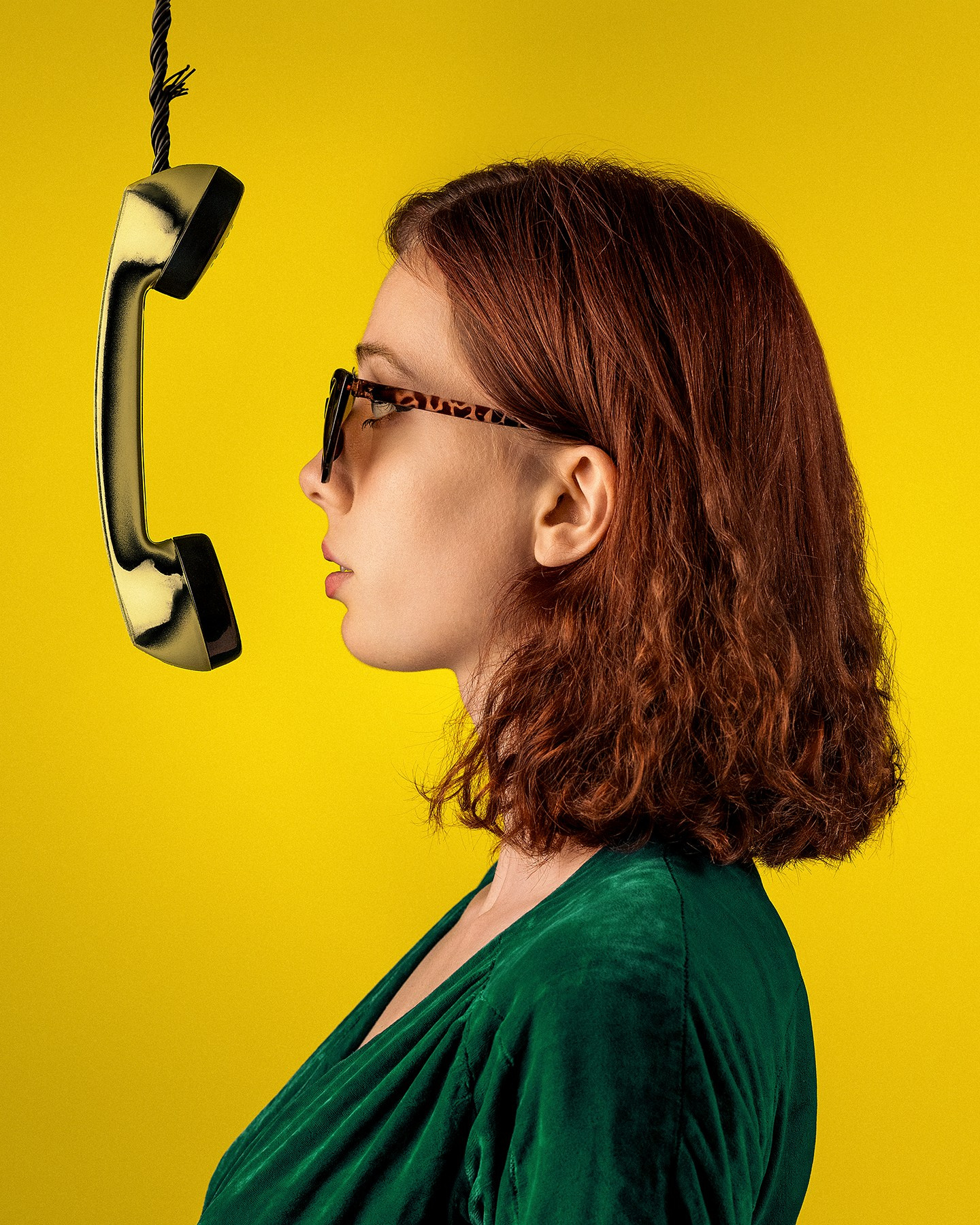 Молодая рыжеволосая девушка на желтом фоне и телефонной трубкой в зеленом платье, съемка на желтом фоне Казань