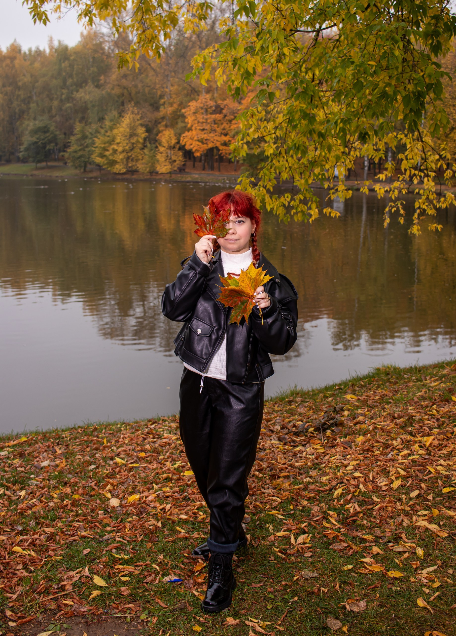 Девушка в кожаной куртке держит осенние листья у озера — осенняя фотосессия, фотограф Карасёва Елена