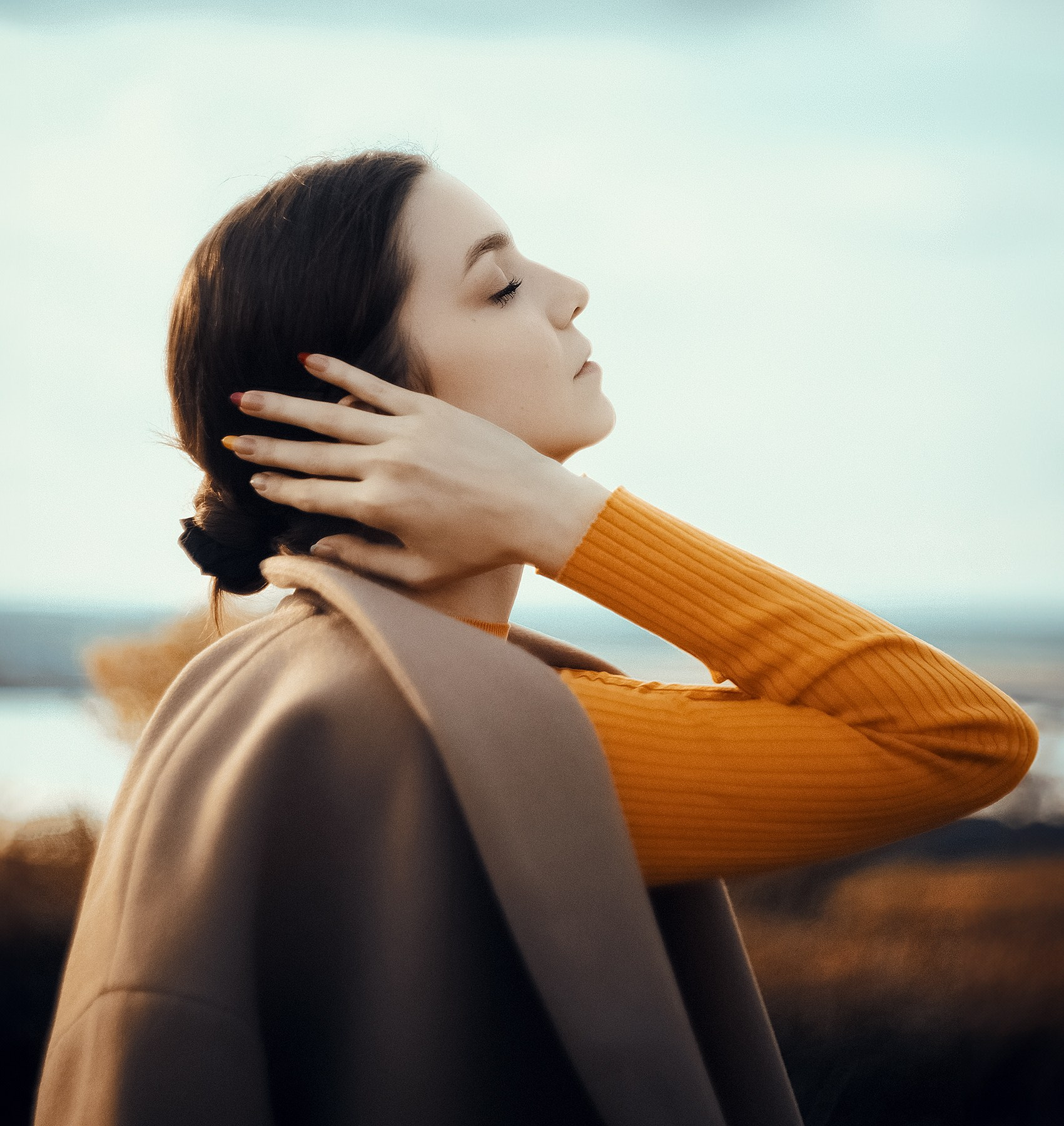 Девушка позирует в оранжевой водолазке и бежевом пальто на природе