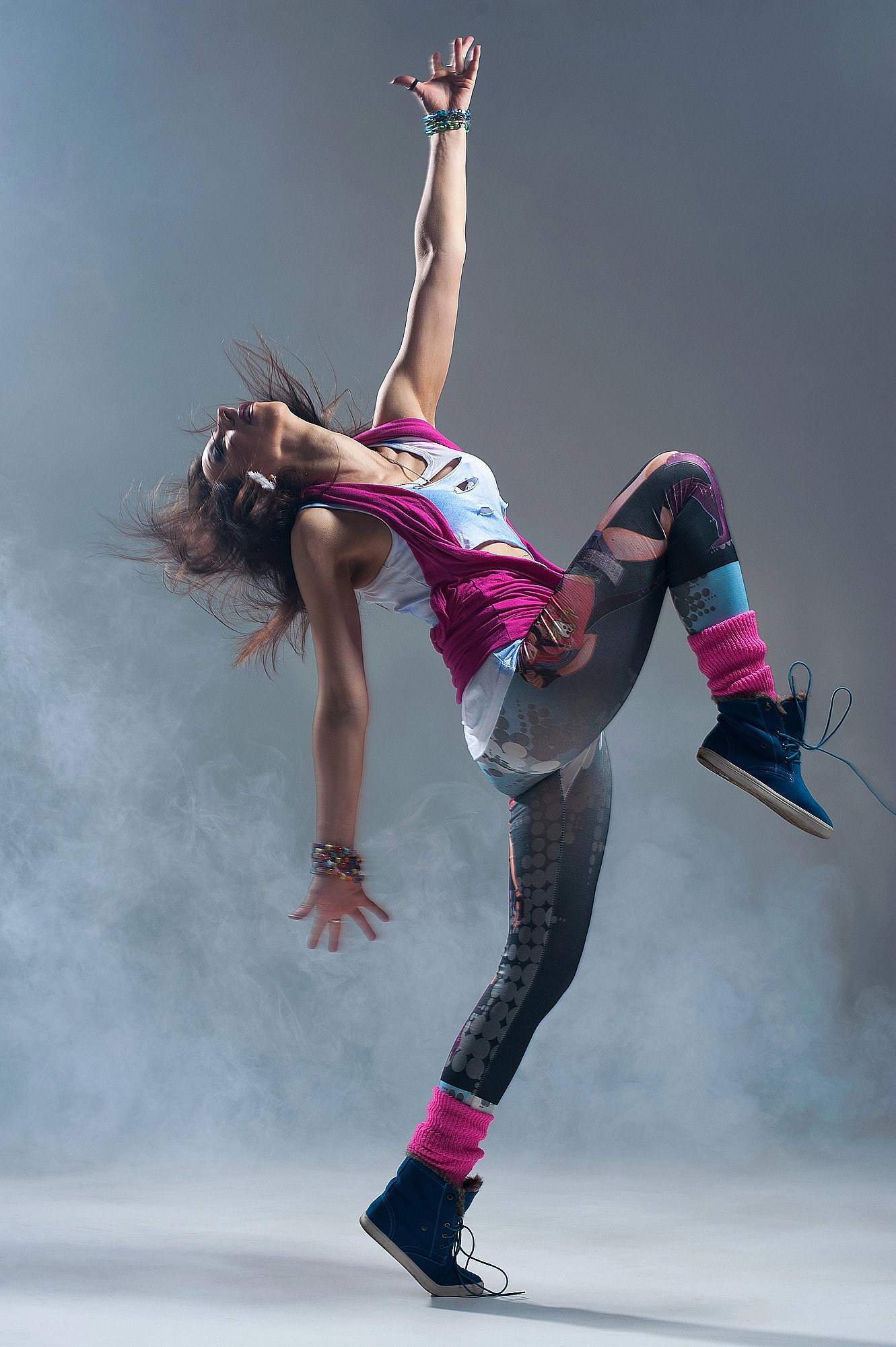 Танцовщица выполняет динамичный элемент в клубах тумана, поднимая руку вверх и создавая мощную диагональ позы. Танцевальная съёмка в Москве и Истринском районе.