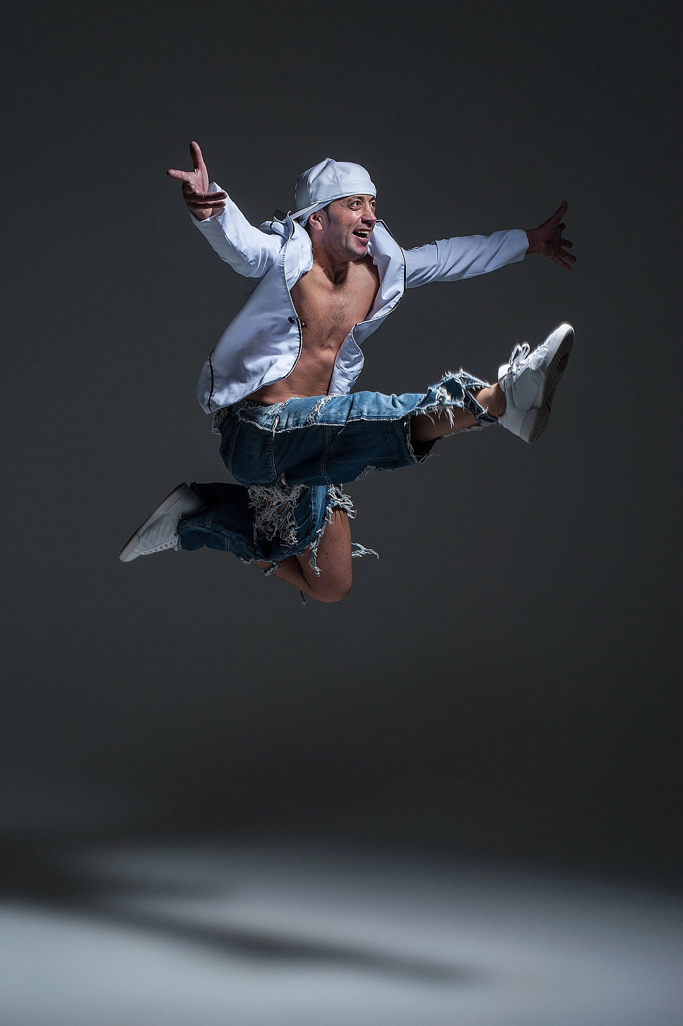 Дансер зависает в воздухе в резком прыжке с согнутыми ногами и активной работой рук. Динамичный танцевальный кадр, Москва и Истринский район.