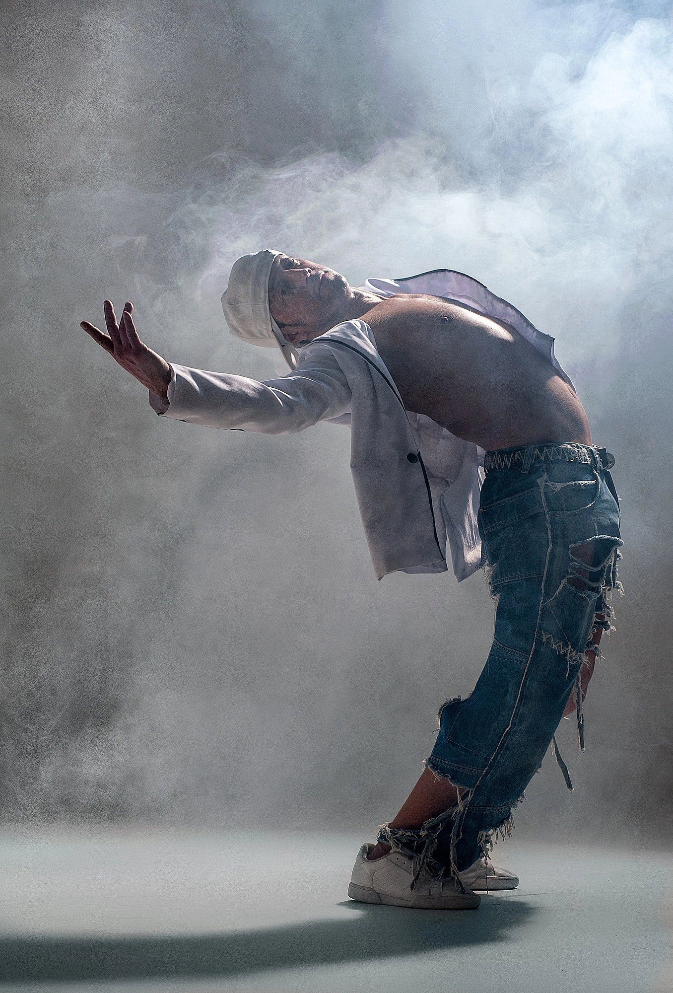 Танцор двигается в густом сценическом дыму, создавая мягкую, атмосферную пластику и кинематографичный силуэт. Танцевальная студийная съёмка в Москве и Истринском районе.
