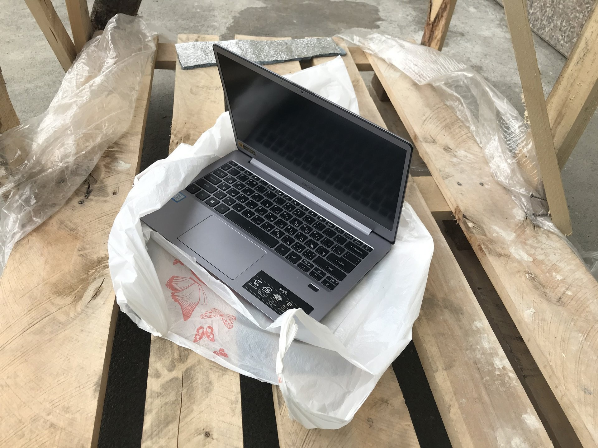 Ноутбук в полиэтиленовом мешке на деревянной подставке.