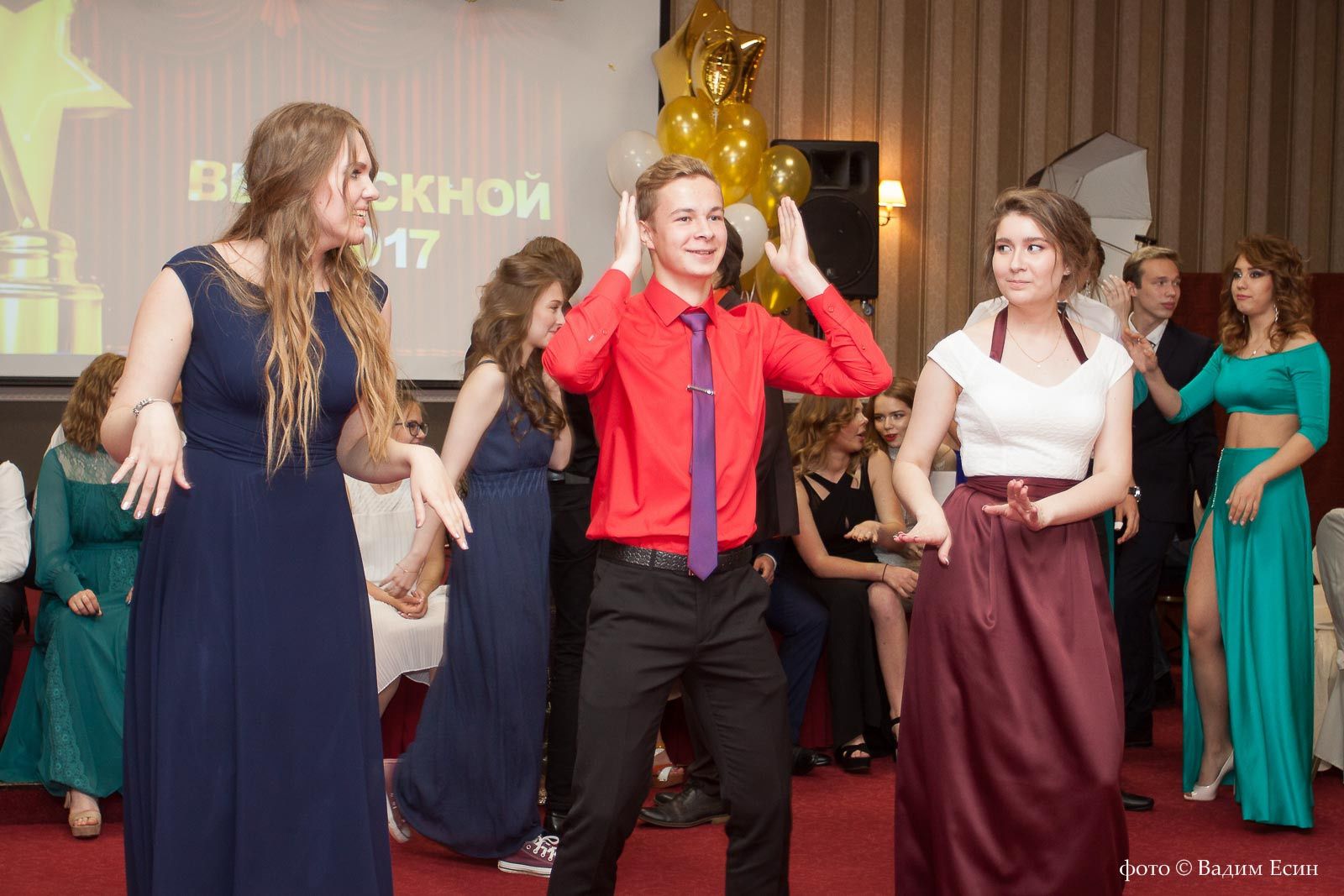 Выпускники 11 класса танцуют быстрый танец на выпускном вечере.