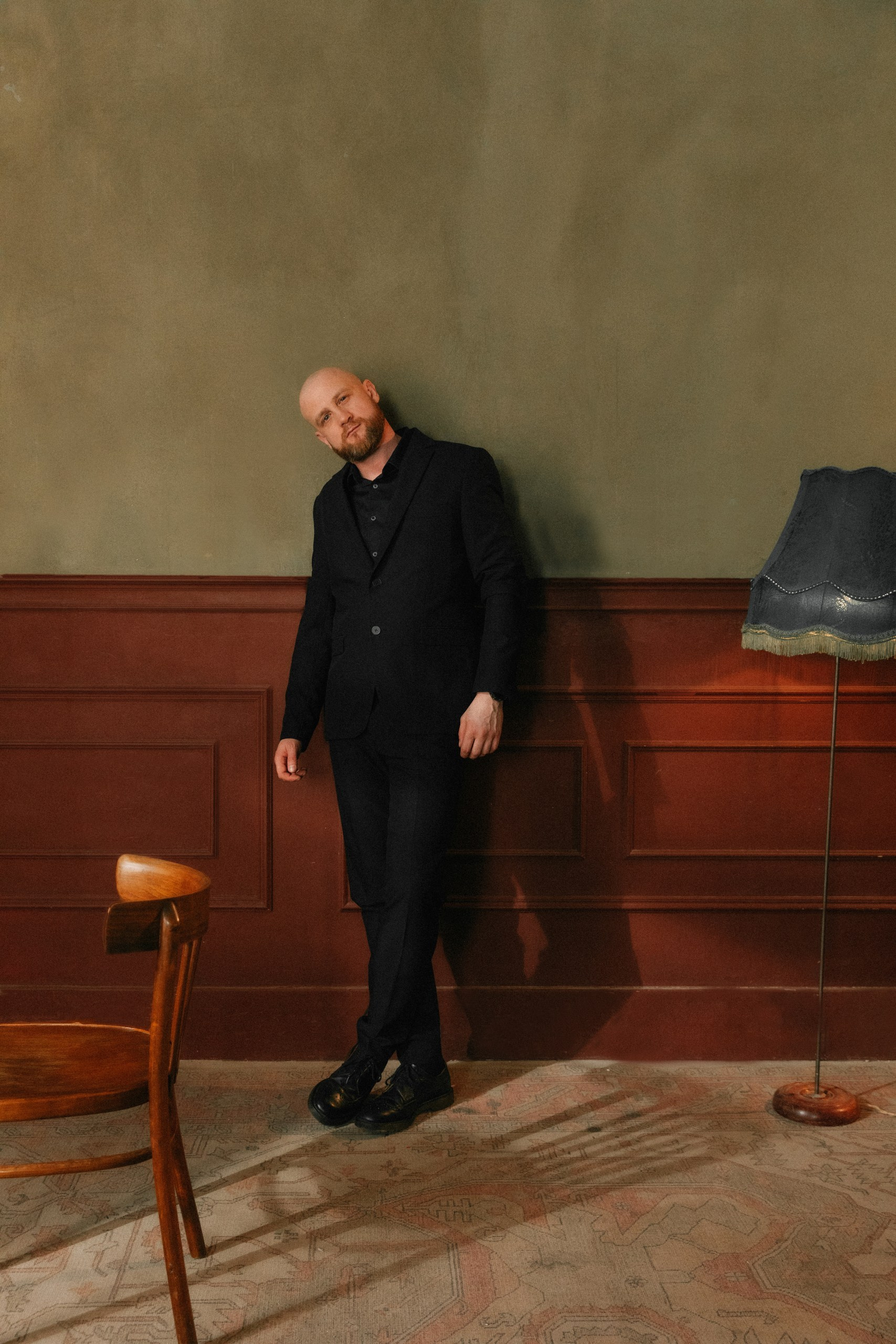 Мужчина в чёрном костюме в ретро-интерьере и винтажным торшером, креативная фотосессия в Санкт-Петербурге.