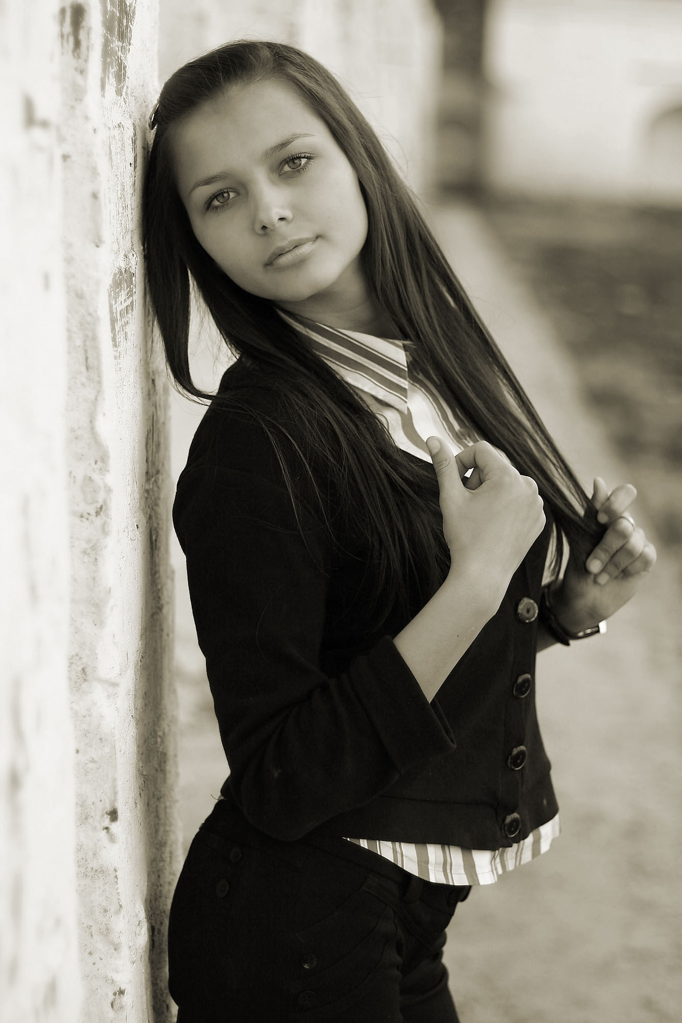 Девушка в черном костюме стоит у стены летом