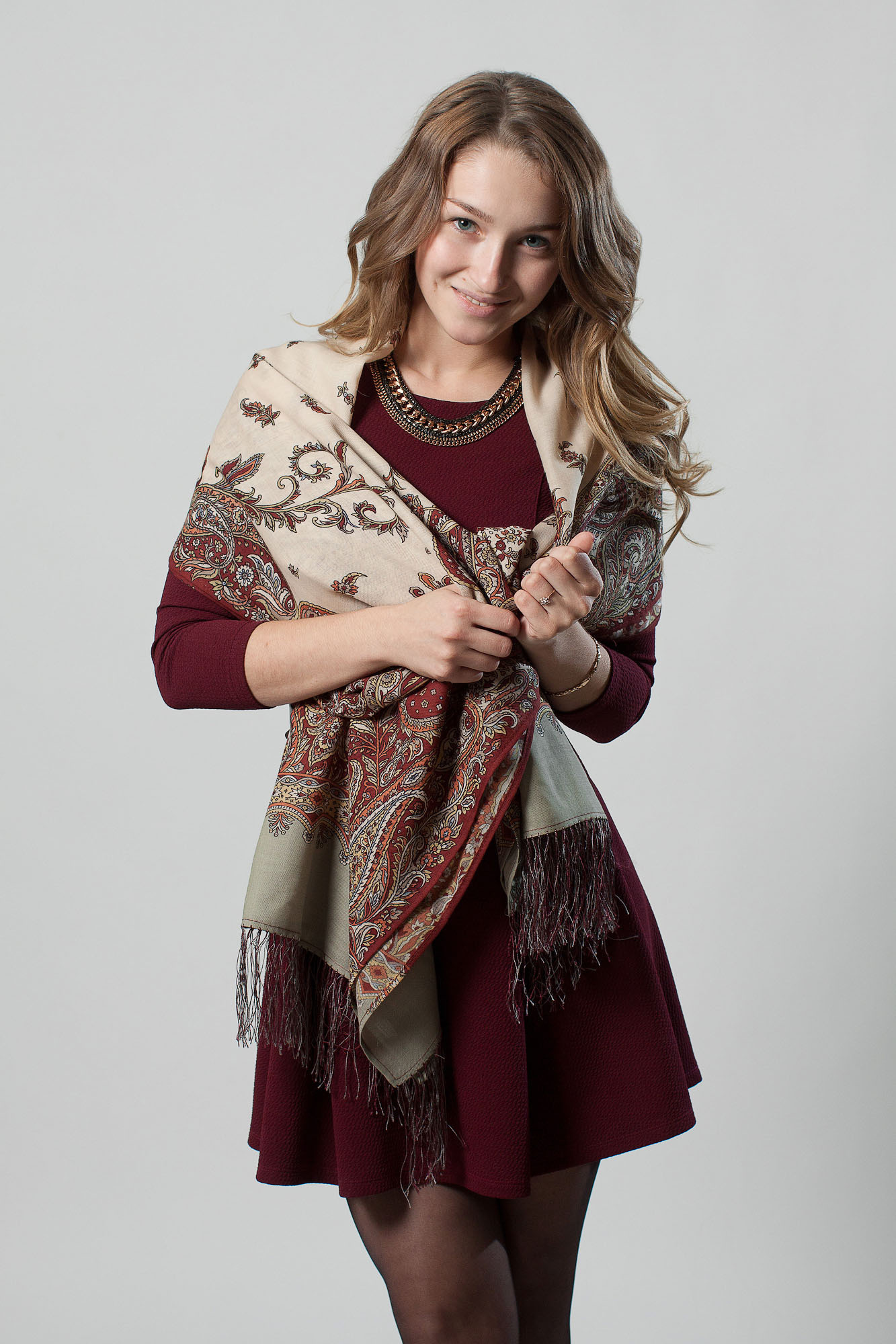 Полноростовой портрет девушки с платком в бордовом платье на сером фоне