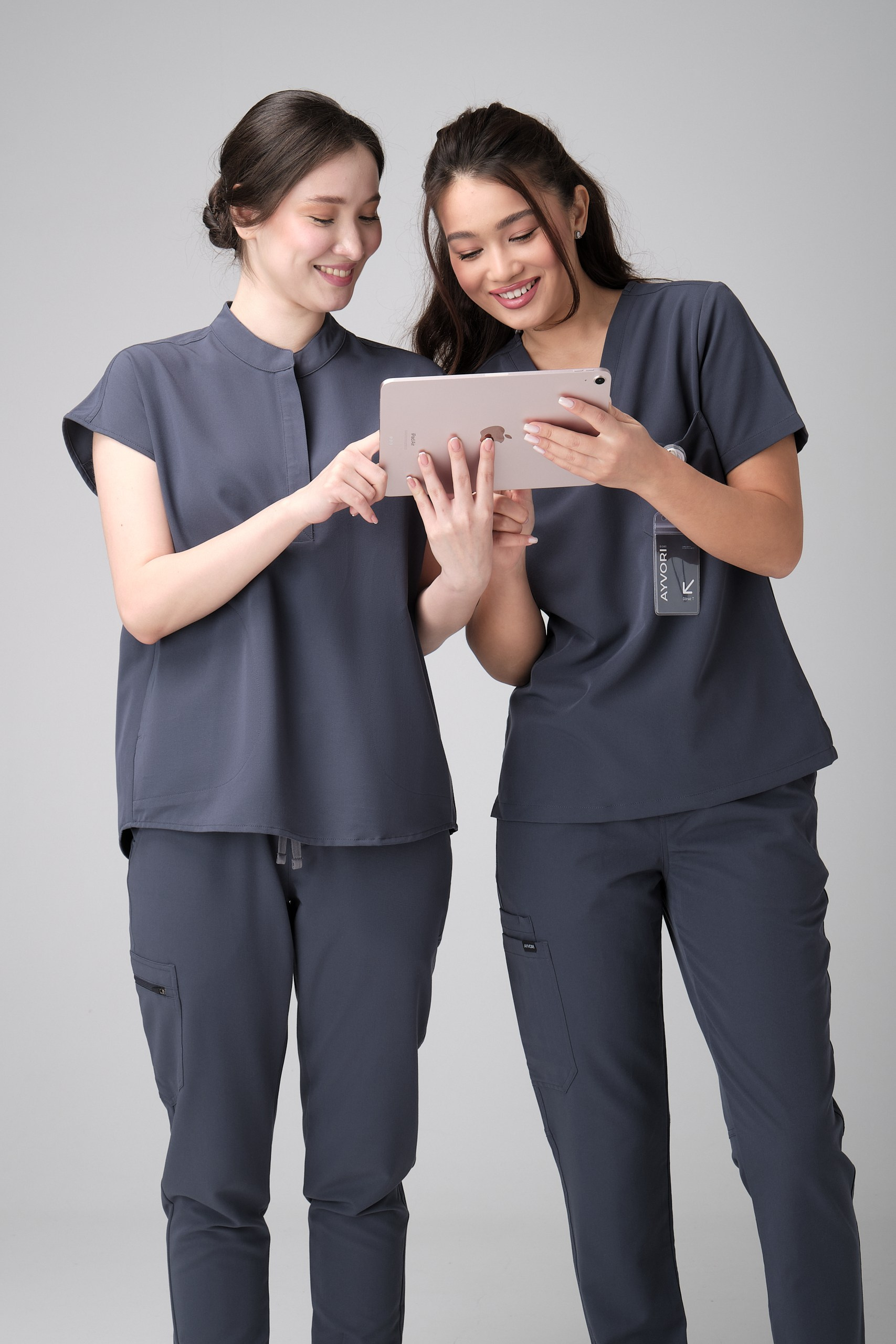 Две модели в медицинской форме смотрят в планшет — лукбук съёмка одежды для медицинских специалистов