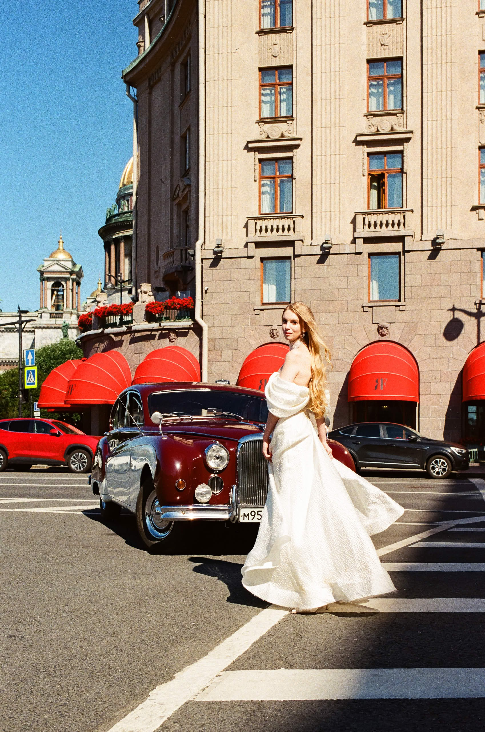 Невеста рядом с ретро автомобилем Jaguar 1959 года во время свадебной фотосессии в Санкт-Петербурге.