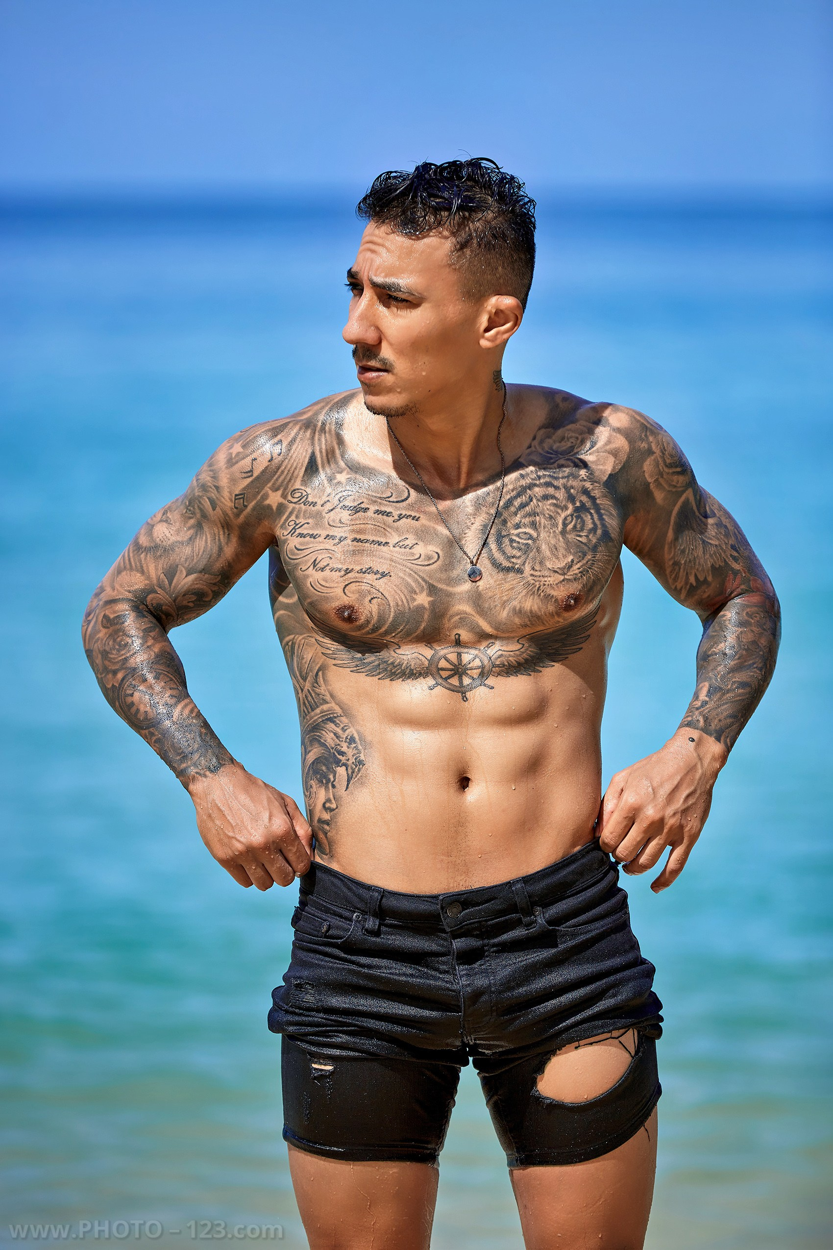 Medium portrait of a tattooed muscular man posing by the ocean in Nha Trang Vietnam