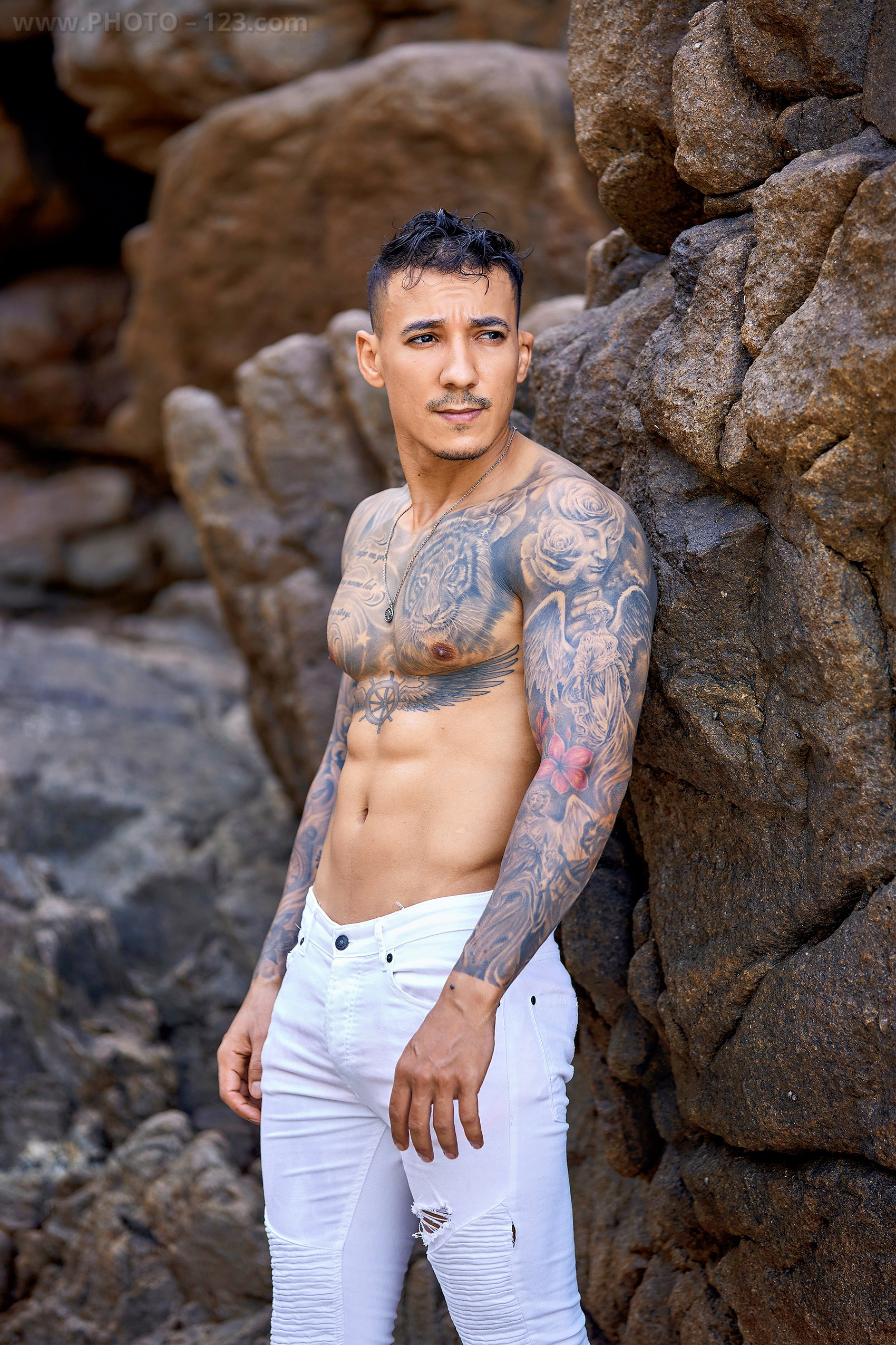 Fitness male portrait session against dramatic rock textures on a Nha Trang beach