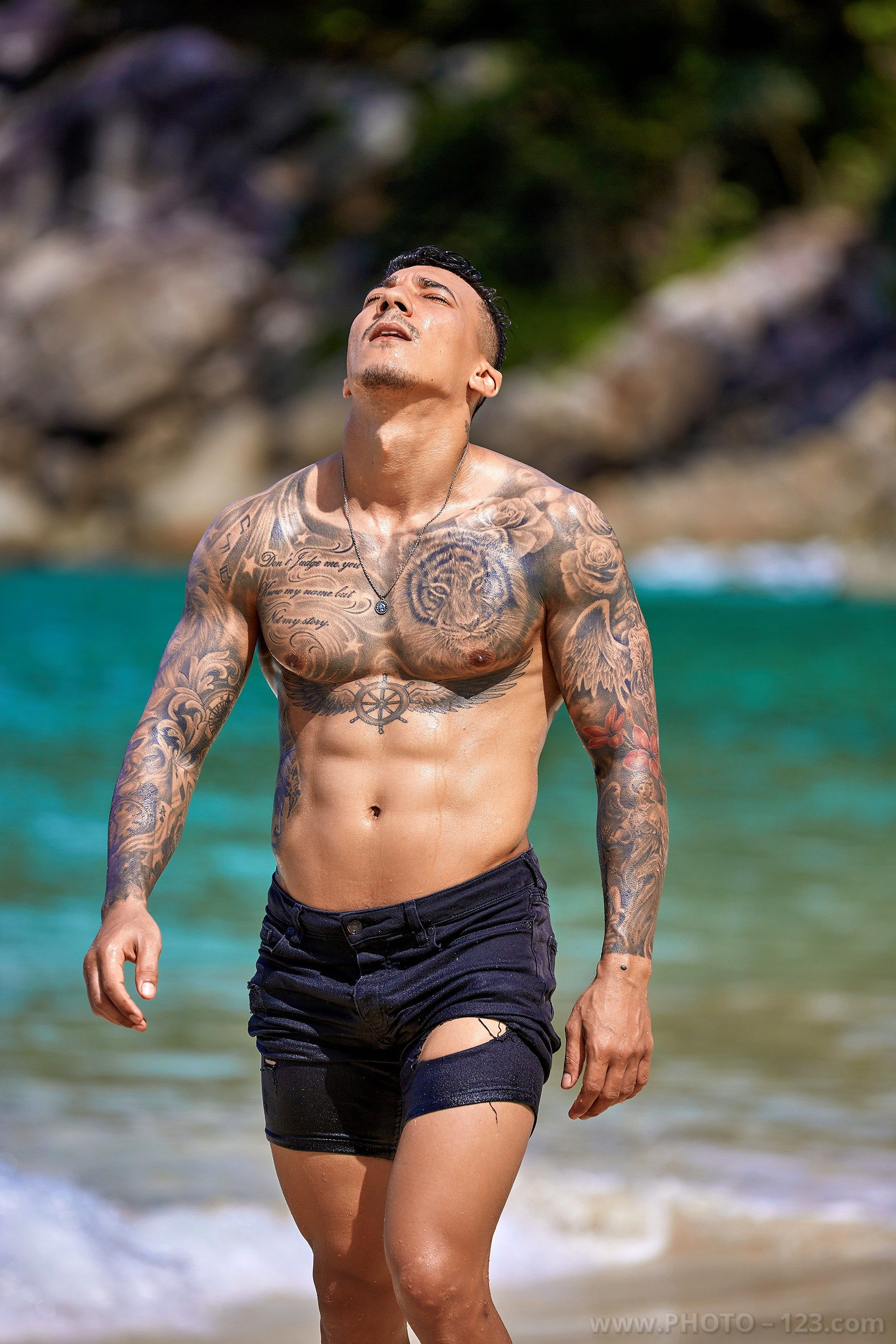 Shirtless muscular man looking up at the sun during a beach photoshoot in Nha Trang Vietnam