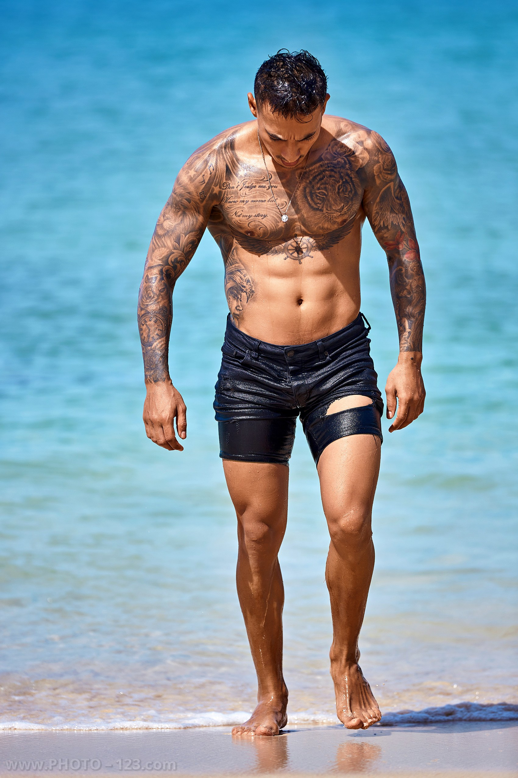 Full-length shot of a muscular tattooed man walking out of the ocean in Nha Trang captured by local photographer