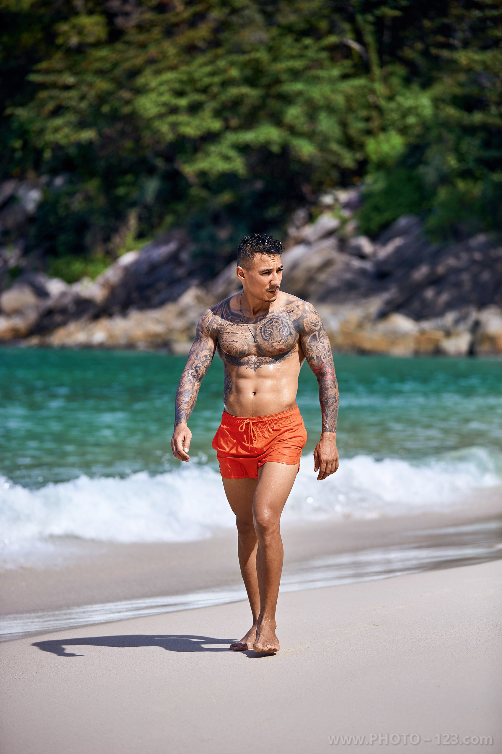 Full-length portrait of a male fitness model walking along the shore during a Nha Trang photoshoot