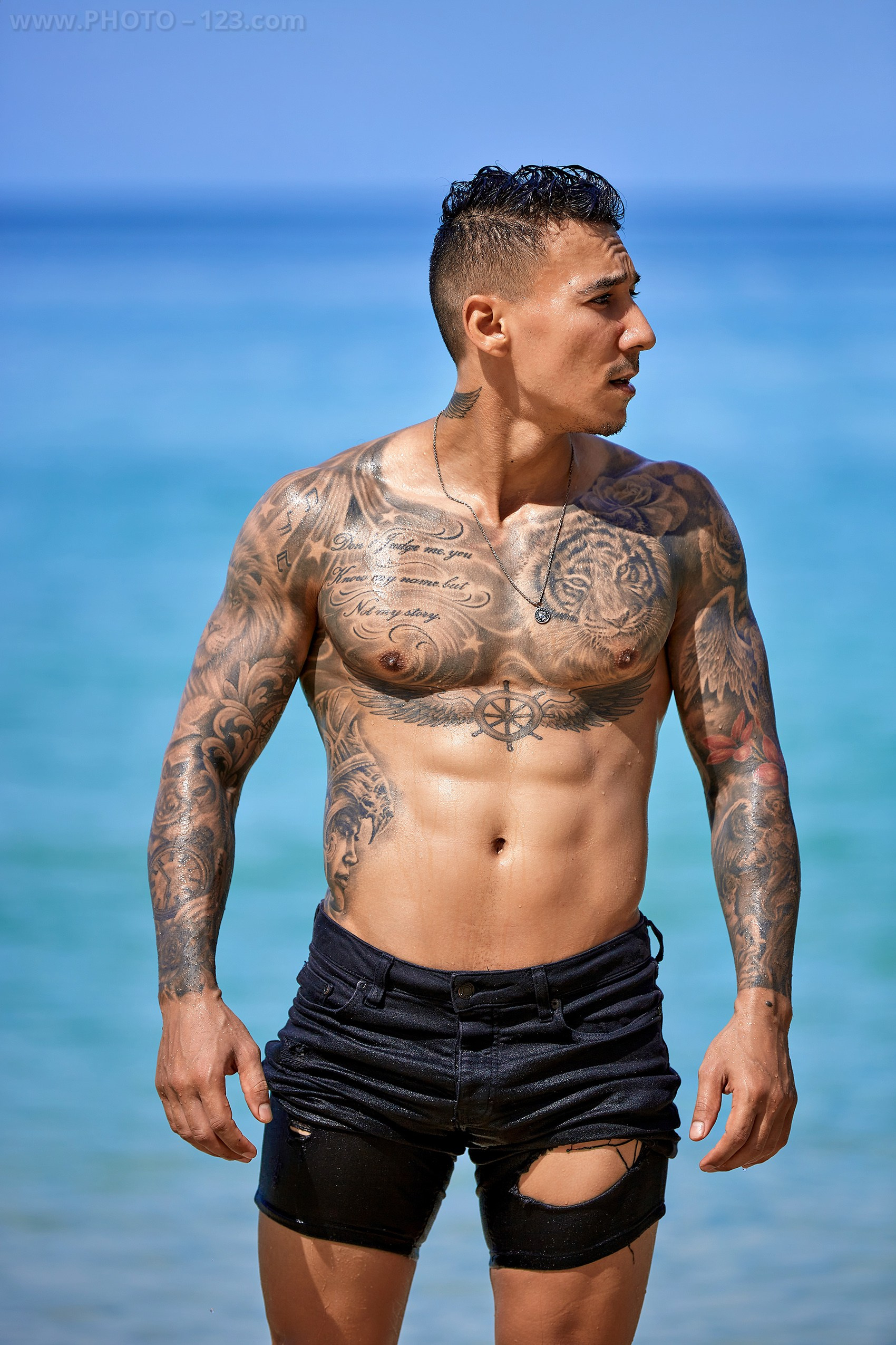 Shirtless athletic male model posing near turquoise sea on a Nha Trang beach