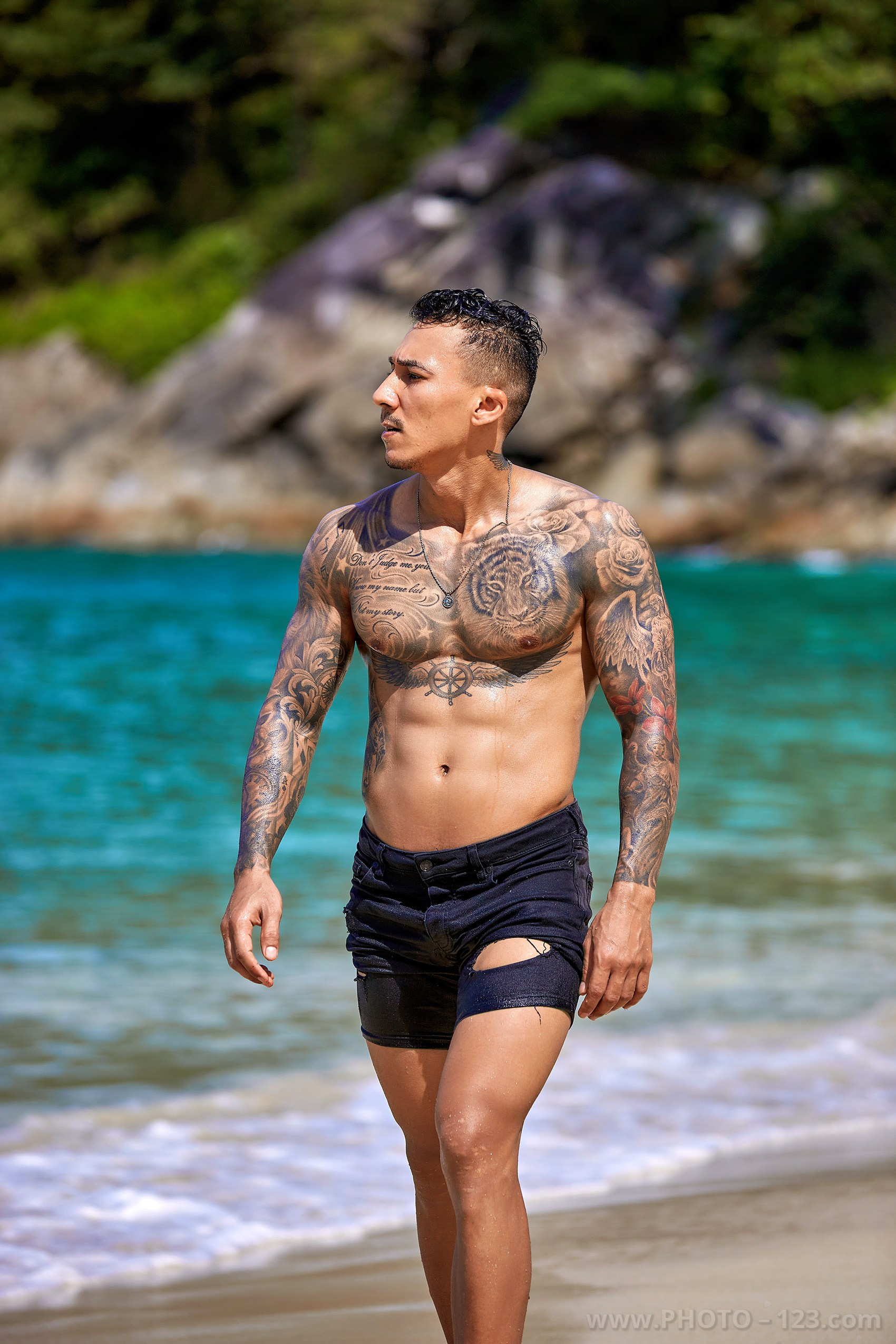 Muscular man walking along turquoise waters during a male photoshoot in Nha Trang