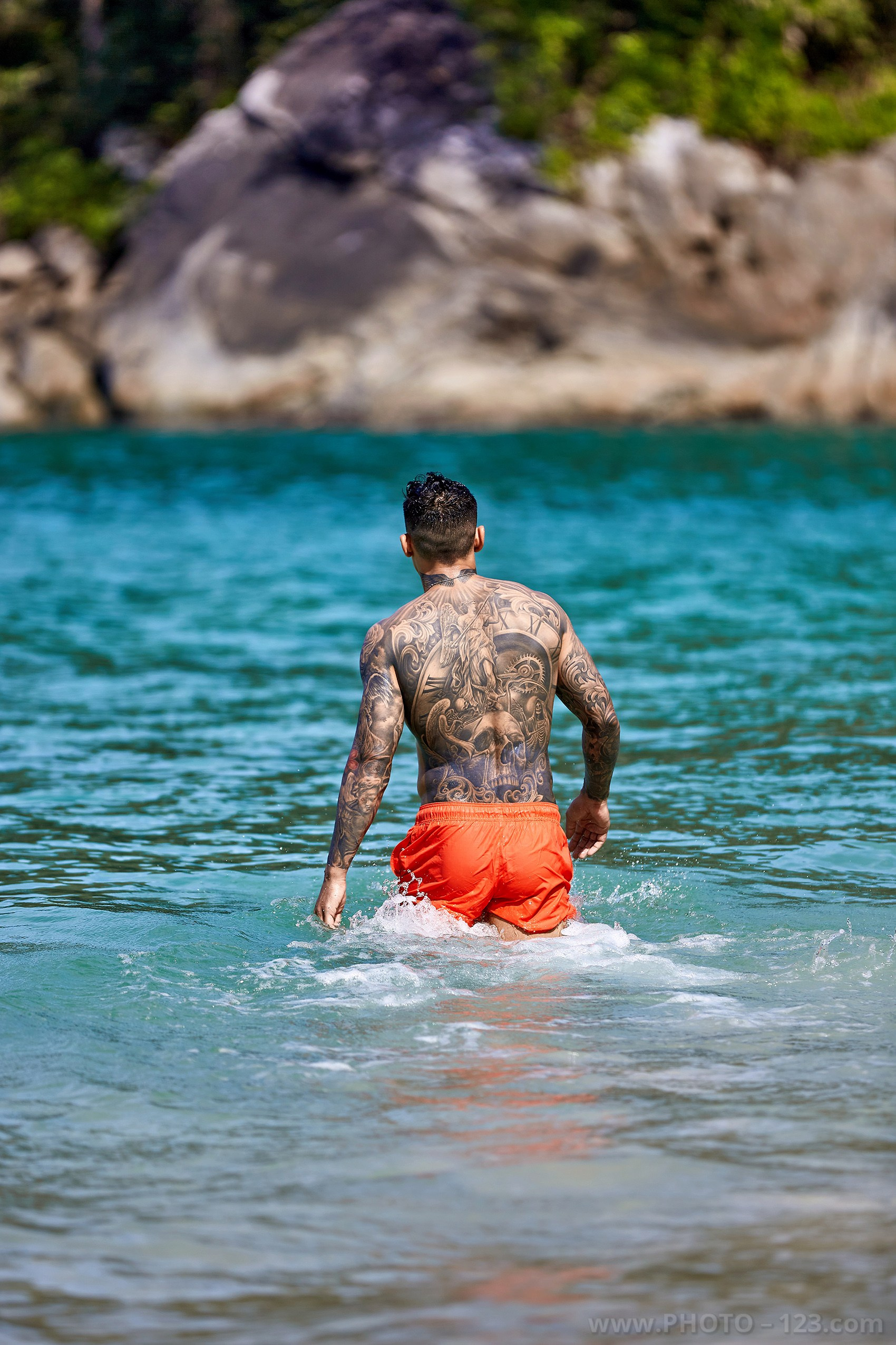 Athletic male model walking into turquoise sea water during a beach photoshoot in Nha Trang Vietnam