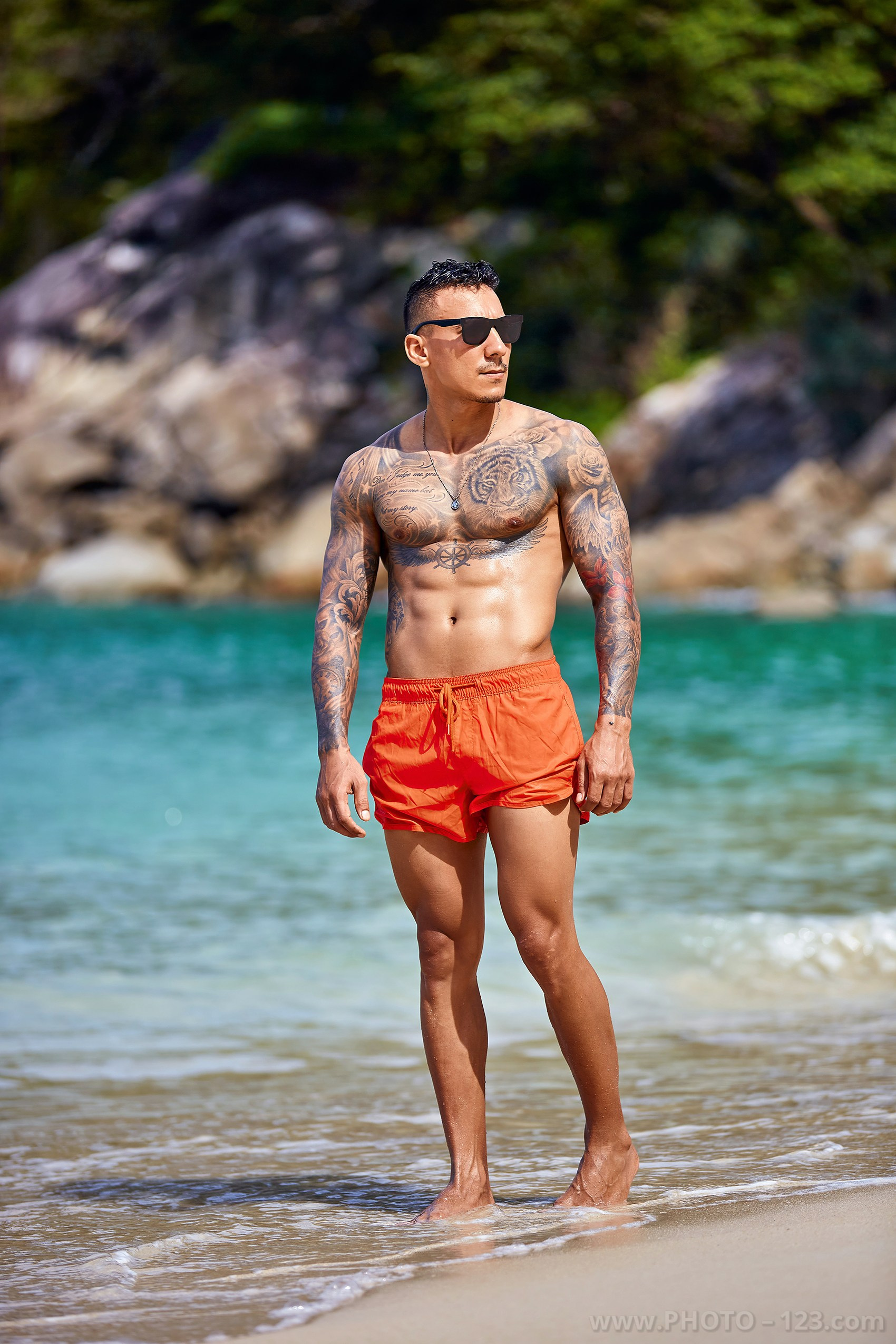Full-length portrait of a muscular man standing in shallow sea water in Nha Trang