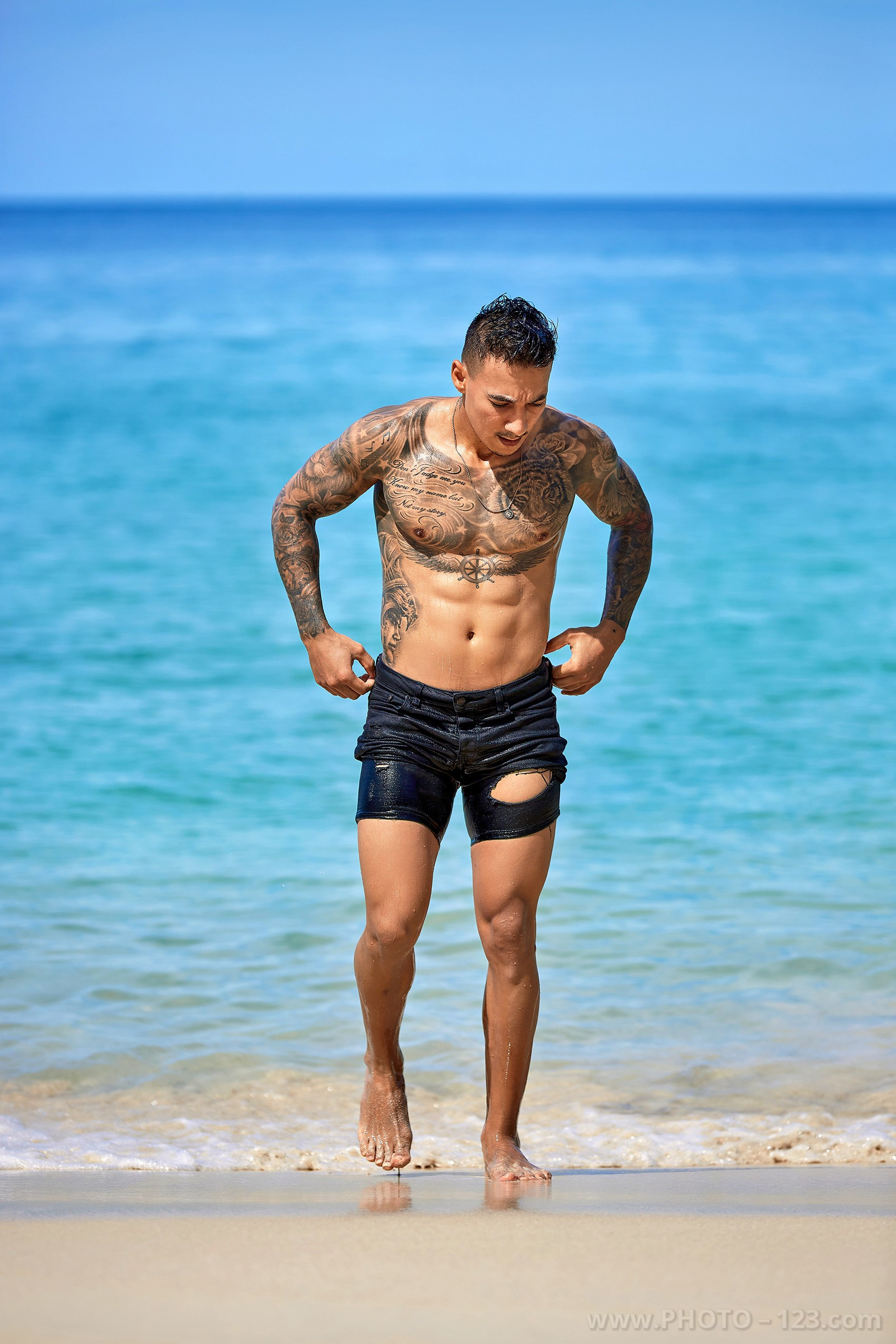 Athletic man walking out of the sea onto sandy beach during a portrait session in Nha Trang