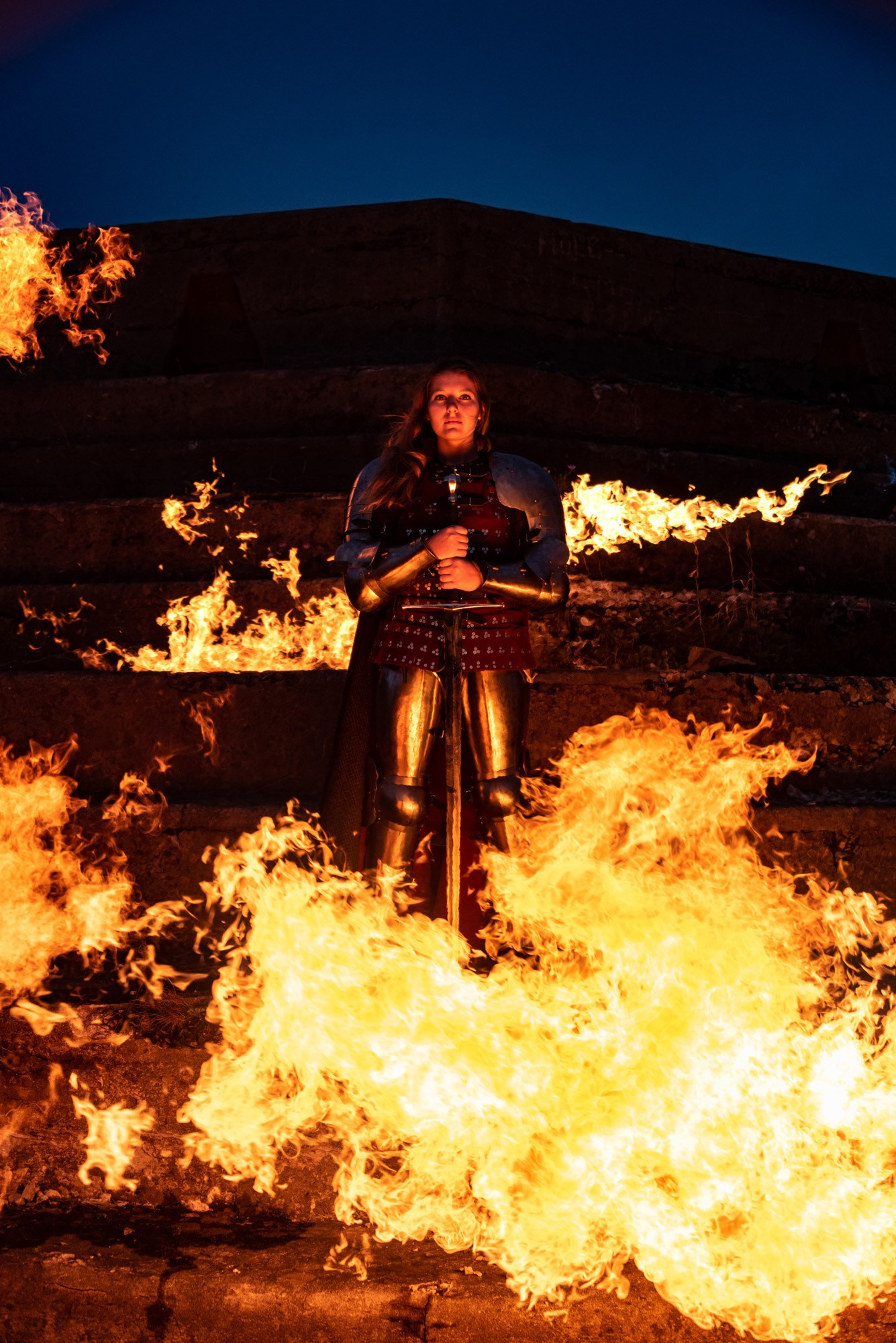 Далишнева ксения огненный фотограф из Владивостока - девушка рыцарь объятая пламенем в металлических доспехах и с печем на каменных ступенях Владивостокской крепости