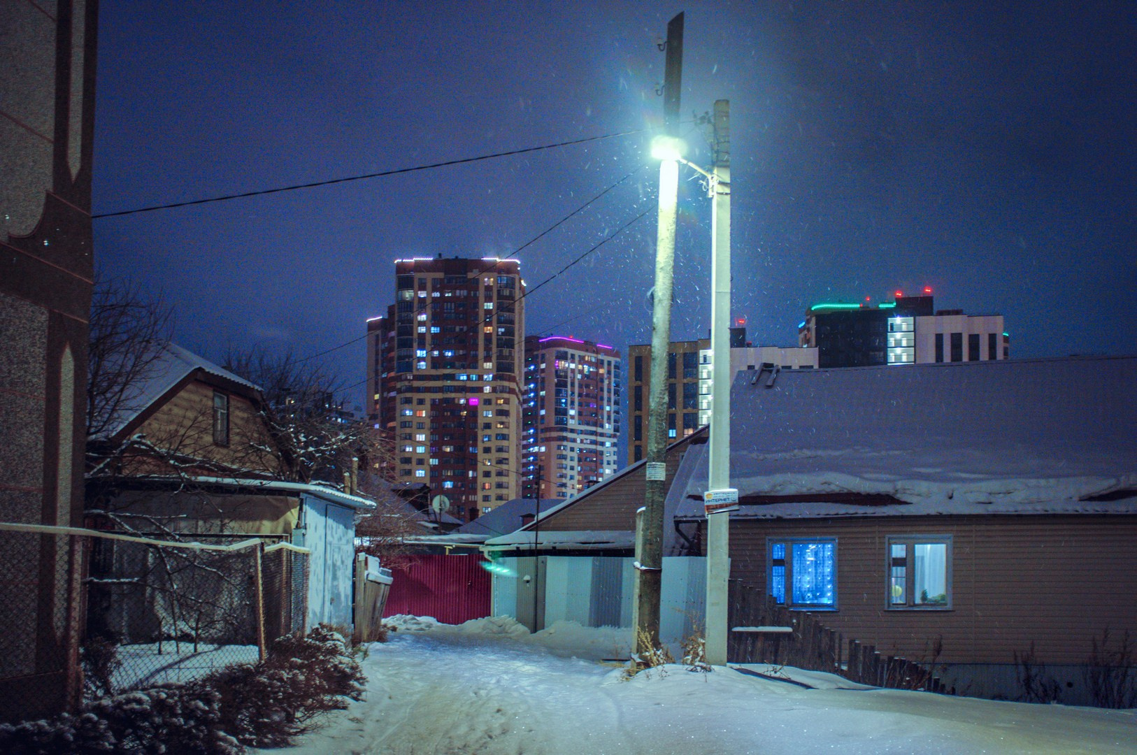 Вечерний двор со снегом, жилая застройка и уличное освещение — атмосфера спального района