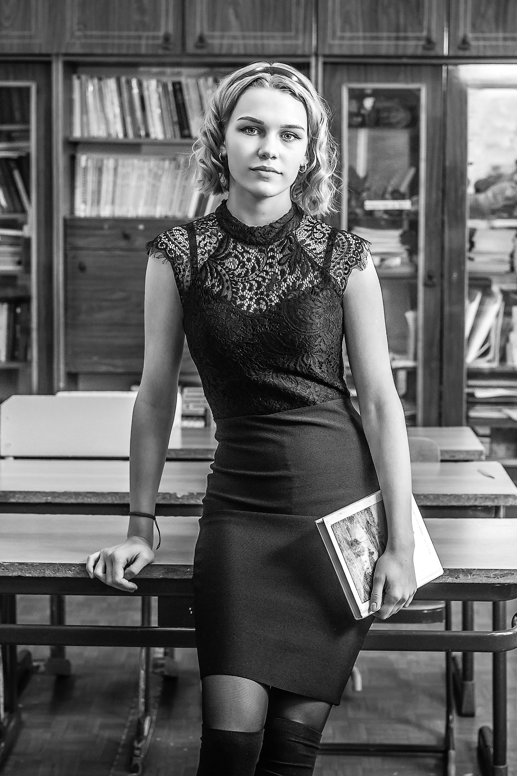 Школьный портрет выпускницы с книгой в библиотеке для выпускного альбома 9–11 класса