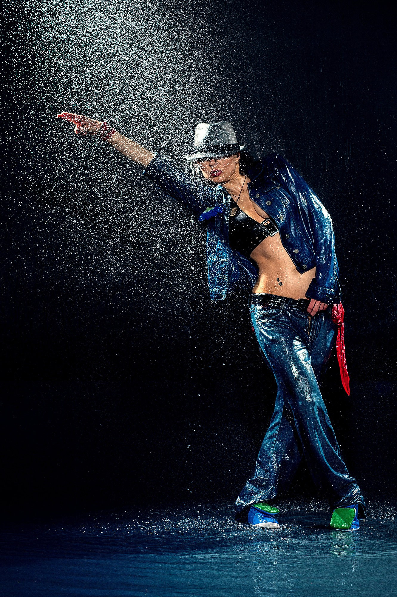 Стрит-танцор под контровым светом выполняет диагональное движение руки, яркие брызги подчеркивают ритм. Фотосъёмка танцев в Москве и Истринском районе.